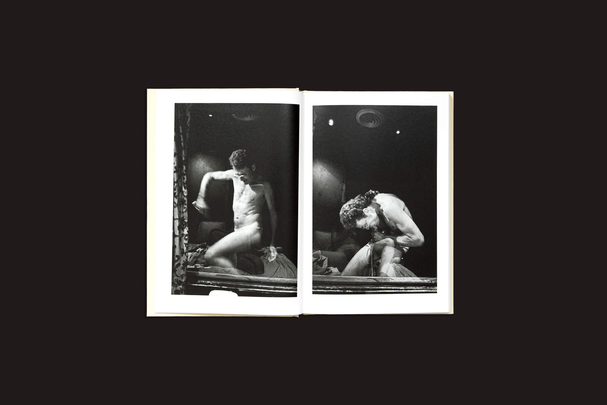 O livro aberto "Cammie Toloui: 5 Dollars For 3 Minutes" da Void apresenta duas fotos em preto e branco de uma estátua nua contra fundos escuros, capturando a essência da sexualidade masculina com poses dinâmicas e expressivas, enfatizando a forma e os detalhes.