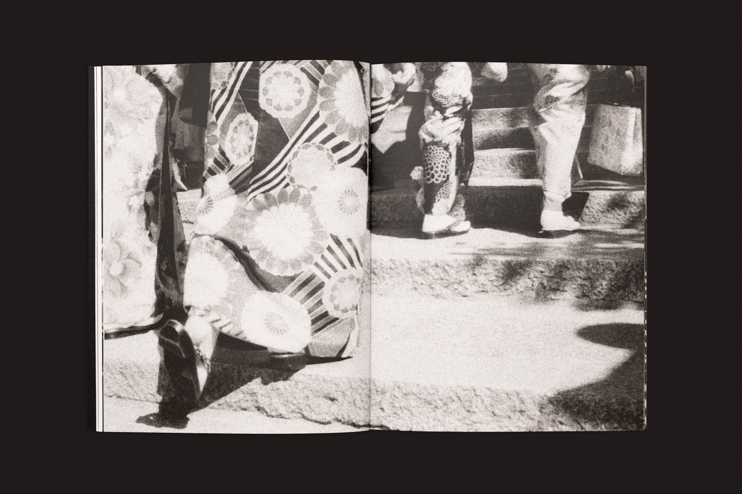 Uma foto em preto e branco captura uma jornada emocional enquanto pessoas com roupas estampadas e calçados tradicionais sobem degraus de pedra. Sombras brincam ao seu redor, evocando uma cena que lembra Layla Motta: Ainda há um longo caminho até minha casa de Selo Turvo.