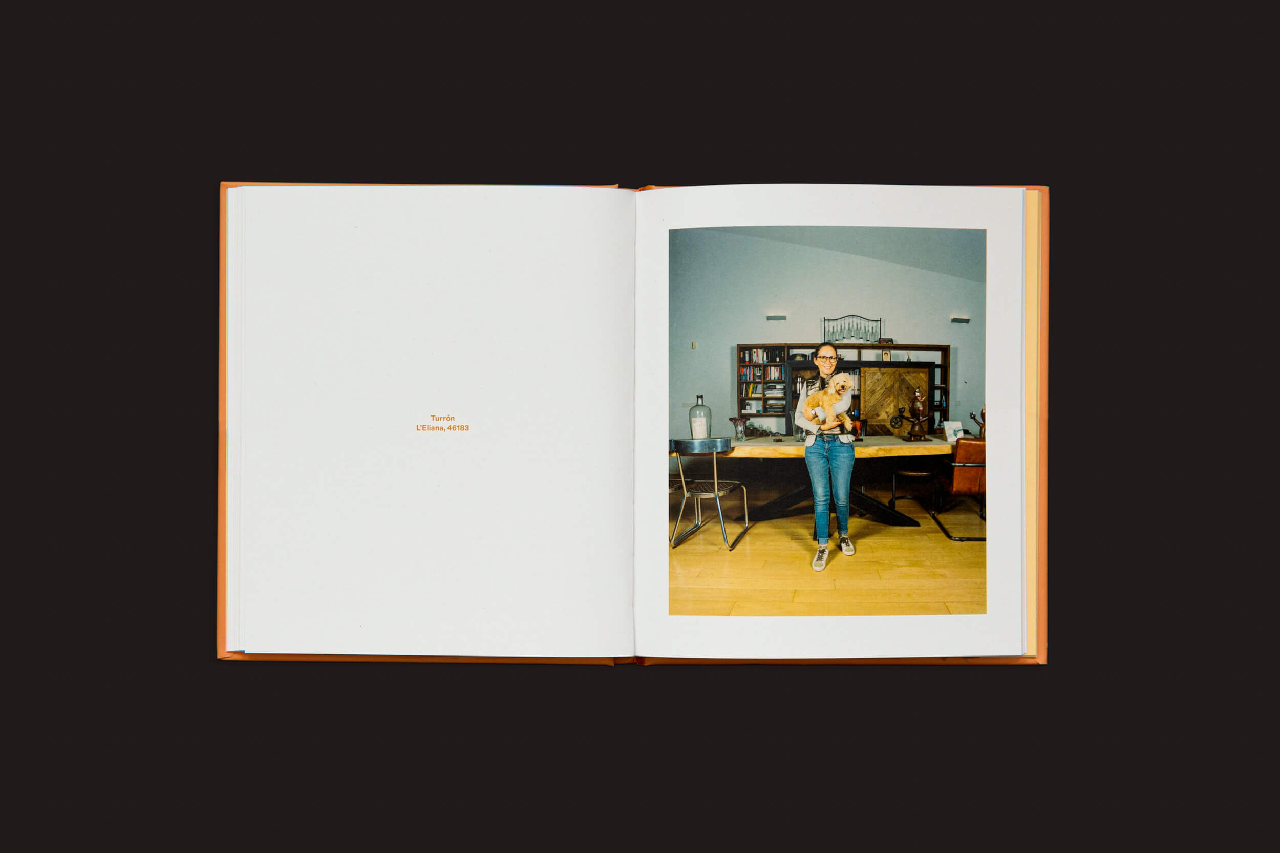 Um livro aberto em um fundo escuro exibe Laura Leal: Apricot Poodle de Handshake. A página da direita apresenta uma fotografia de uma pessoa em uma sala com uma mesa de madeira e itens variados, refletindo dinâmicas sociais. A página da esquerda lê Tokyo 13 Nov 2022.