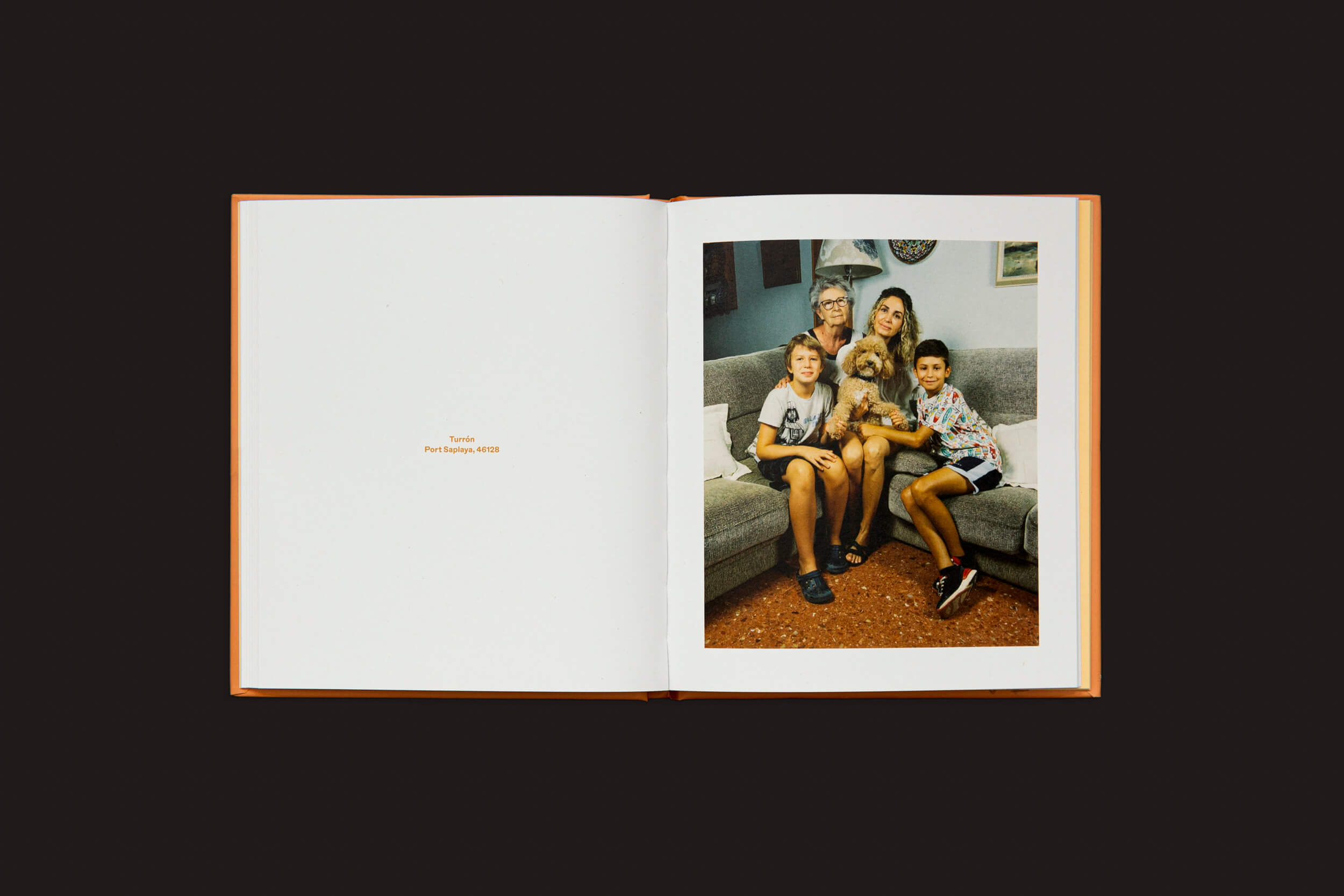 Um livro aberto, Laura Leal: Apricot Poodle da Handshake, repousa sobre uma superfície escura. Na página direita, um retrato de família de dois adultos, duas crianças e seu brincalhão Apricot Poodle descansando em um sofá exala aconchego. O pequeno texto diz Tavira Paolo Salvioni 2020.