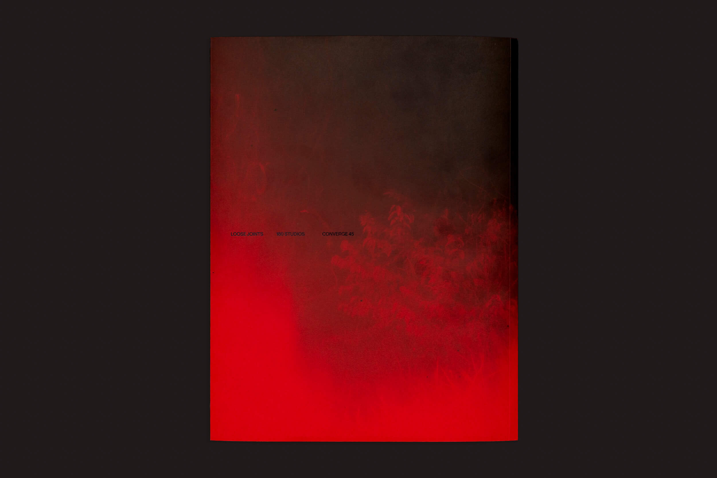 O pôster Richard Mosse: Broken Spectre da Loose Joints apresenta um impressionante gradiente escuro do preto ao vermelho intenso, com o sutil texto central FOOL DOVE / BATWANG / CHAMPERS sobre um fundo esfumaçado, que lembra os danos ambientais na Amazônia.