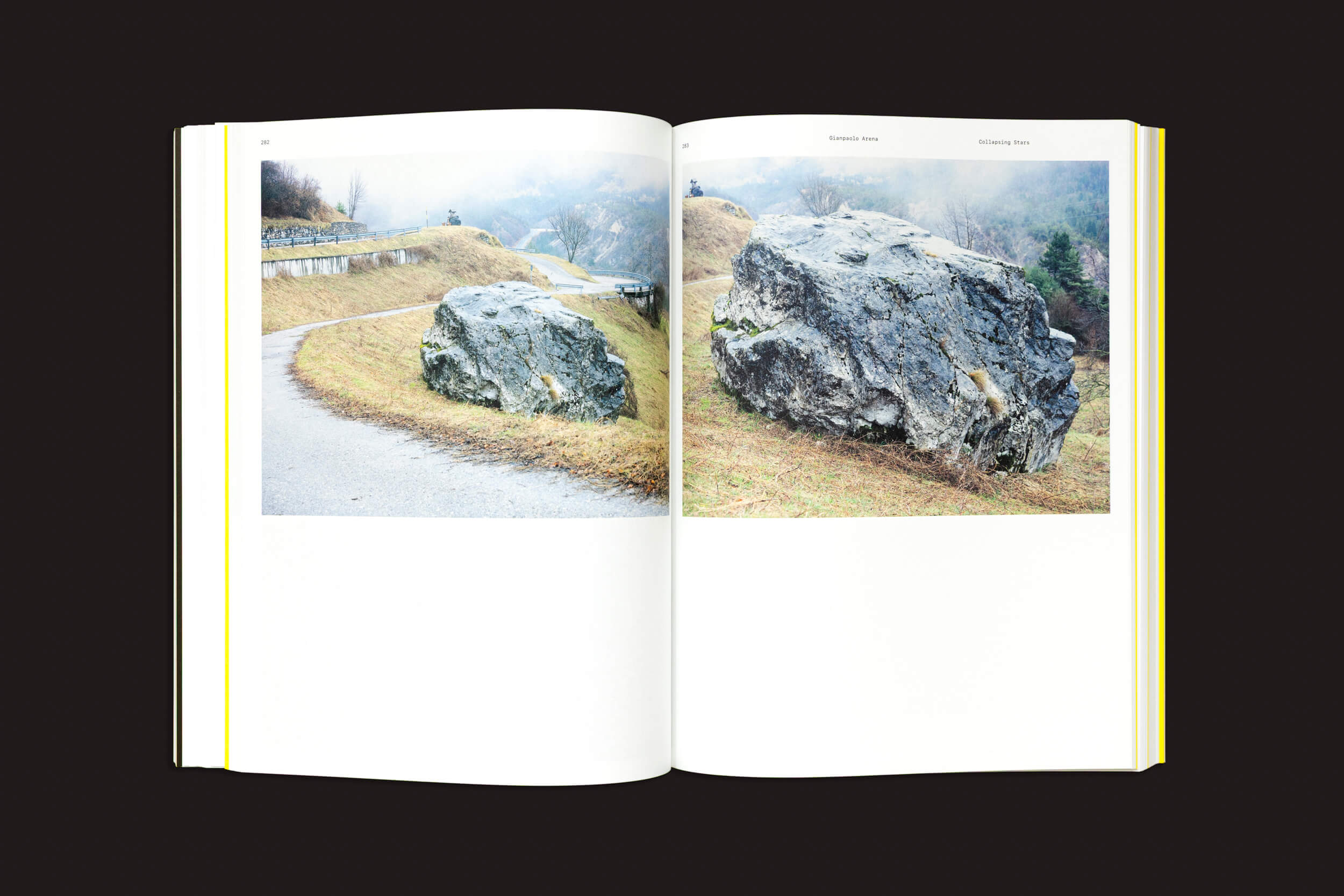 Um livro aberto, CALAMITA/À – Uma investigação sobre a catástrofe de Vajont: v/a, da Fw:Books, exibe duas fotos semelhantes de uma grande rocha cinza na grama perto de um caminho curvo e enevoado — cada uma tirada de ângulos ligeiramente diferentes.