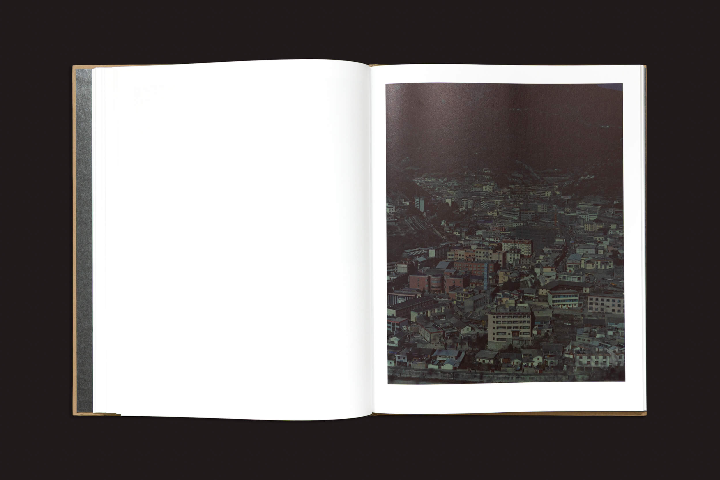 Um livro aberto de Skinnerboox mostra uma página em branco à esquerda e uma foto aérea de uma cidade densamente povoada à direita, encapsulando as complexidades do "Sonho Chinês" de Teresa Eng.