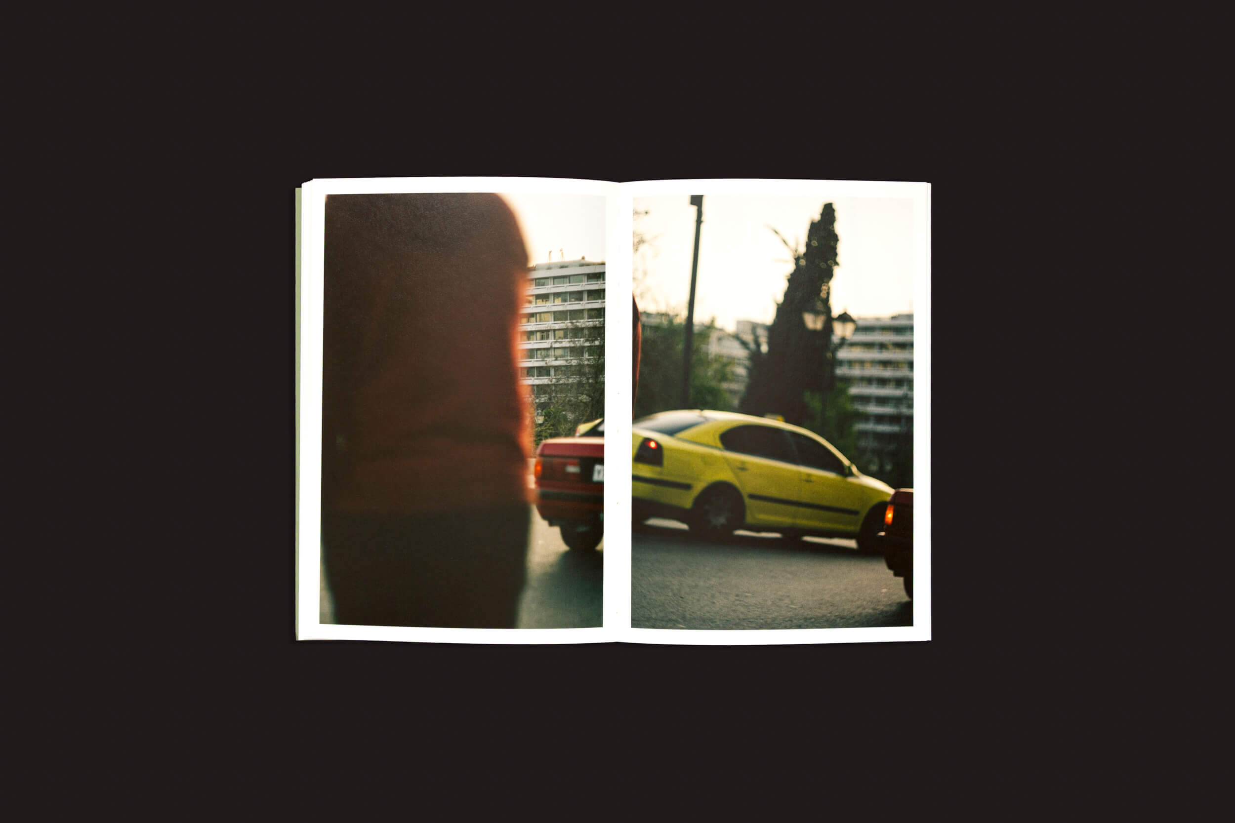 Em "Simon Bray: Dear Kairos", de Skinnerboox, um livro aberto revela fotos desfocadas: a da esquerda mostra as costas de uma pessoa, enquanto a da direita mostra um carro amarelo em uma rua de Atenas com prédios que se misturam suavemente. O tom cálido evoca sussurros da passagem suave do tempo em ritmo grego.