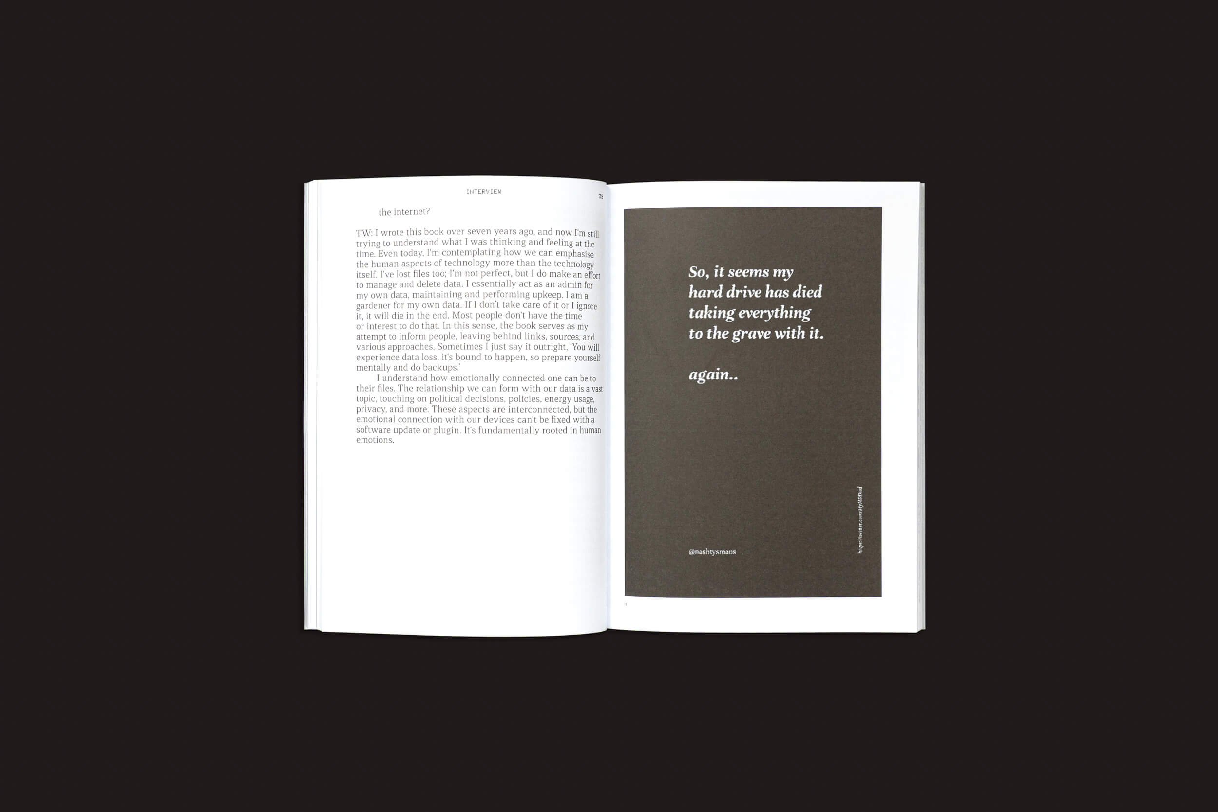 Um livro aberto sobre uma superfície preta apresenta a página esquerda com texto em fonte serifada e a página direita exibe uma citação sobre a morte digital de "Death Design Data", de Cecilia Casabona e Ginevra Petrozzi, refletindo o tema de rituais contemporâneos de Onomatopee.