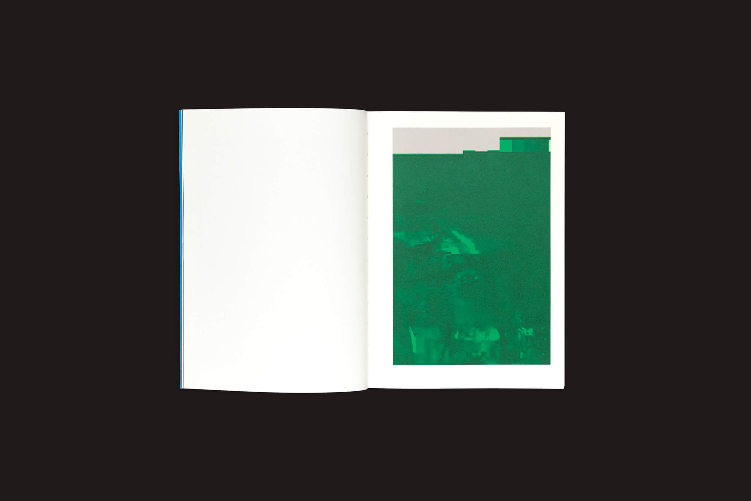 Um livro aberto sobre uma superfície escura exibe Taysir Batniji: Disruptions by Loose Joints. A página da esquerda está em branco, enquanto a da direita apresenta uma arte minimalista — um retângulo abstrato verde com formas indistintas e uma faixa superior mais clara, evocando sutis interrupções no estilo de Batniji de Gaza.