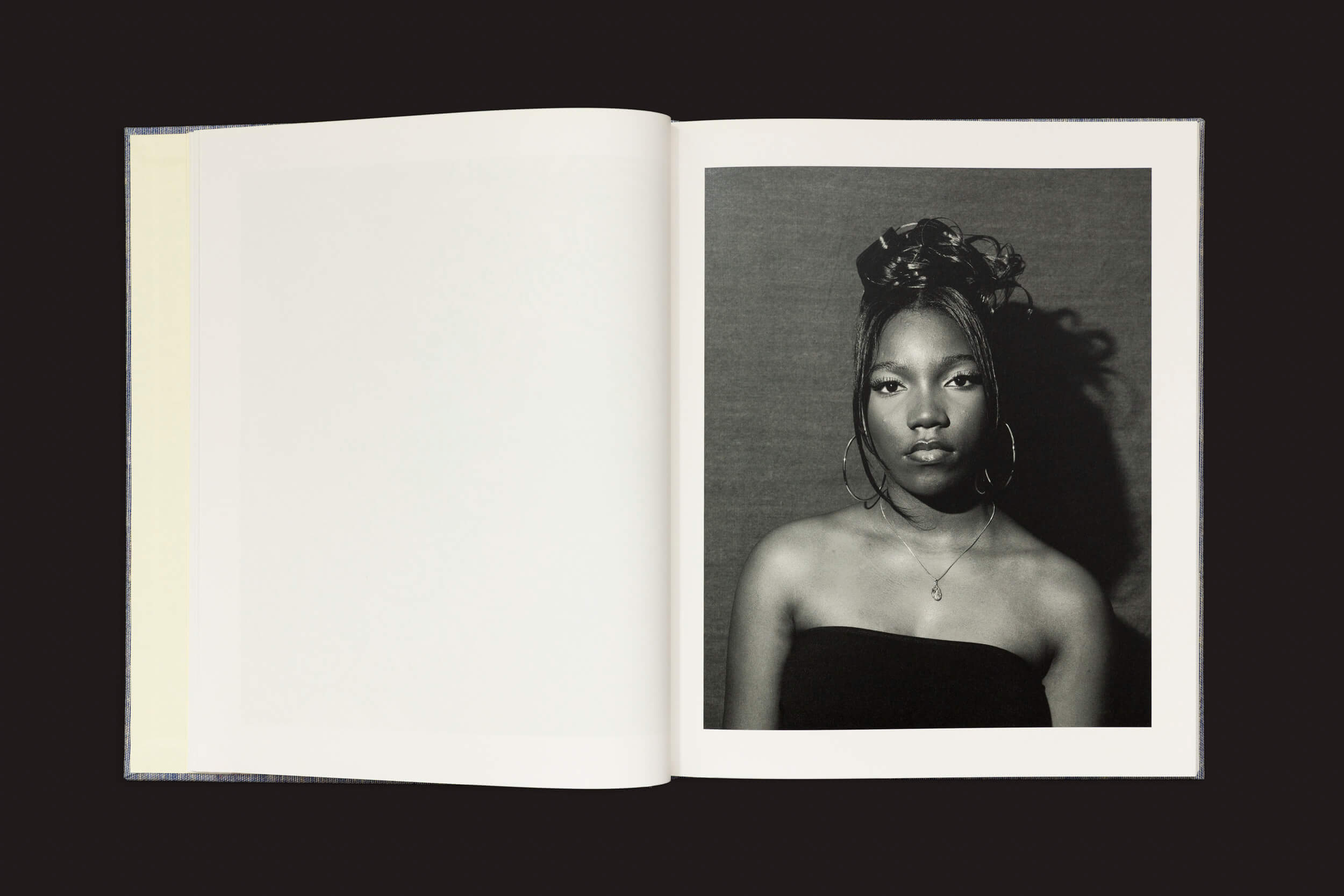 Em Rahim Fortune: Hardtack de Loose Joints, um livro aberto revela um retrato em preto e branco de uma jovem mulher com grandes brincos de argola e um top sem alças. Seu cabelo está penteado em um elegante coque, refletindo tradições culturais. A página da esquerda permanece em branco, pronta para mais histórias.