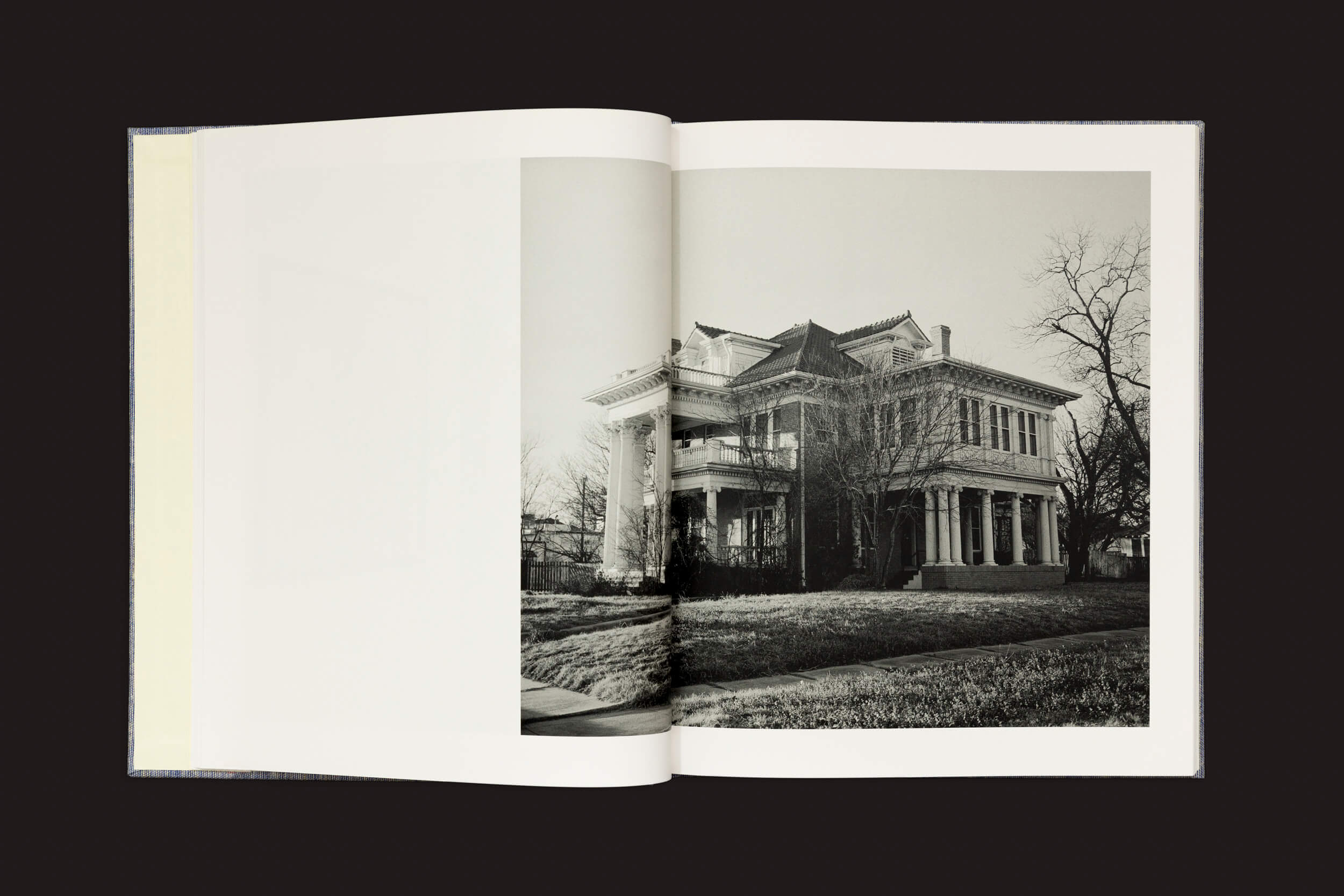 Uma cópia de Rahim Fortune: Hardtack da Loose Joints mostra um livro aberto com uma foto em preto e branco de uma velha casa de dois andares. A paisagem de inverno austera, com árvores sem folhas e grama, evoca a América pós-emancipação e realça sua aura histórica.