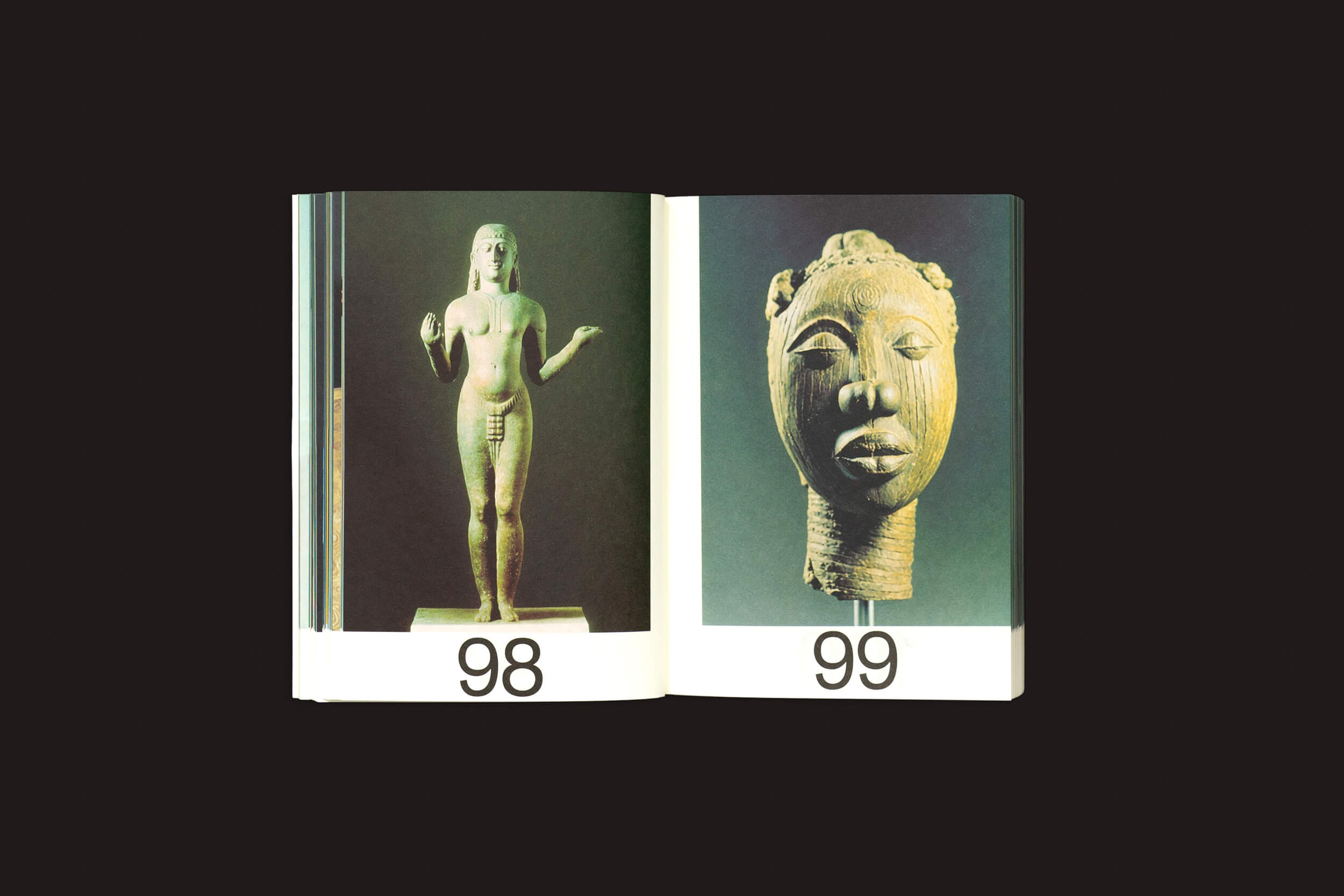 Um open mostrando duas páginas de Martín Bollati: Hermes/Unesco da SED Editorial; a página da esquerda apresenta uma fotografia de uma estátua feminina nua com a etiqueta 98 ligada a civilizações antigas, a página da direita apresenta uma escultura de cabeça em madeira evocativa de tesouros de ruínas assinalada com o número 99.