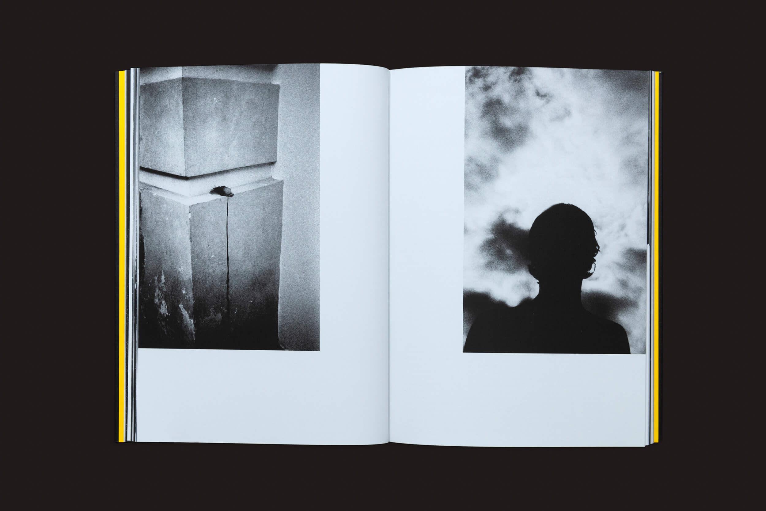 Em Artur Lahoz: Klexos, de Selo Turvo, um livro aberto sobre um fundo escuro revela duas fotografias em preto e branco: uma estrutura de concreto com um pequeno objeto e uma silhueta contra um céu nublado, capturando a essência da memória.