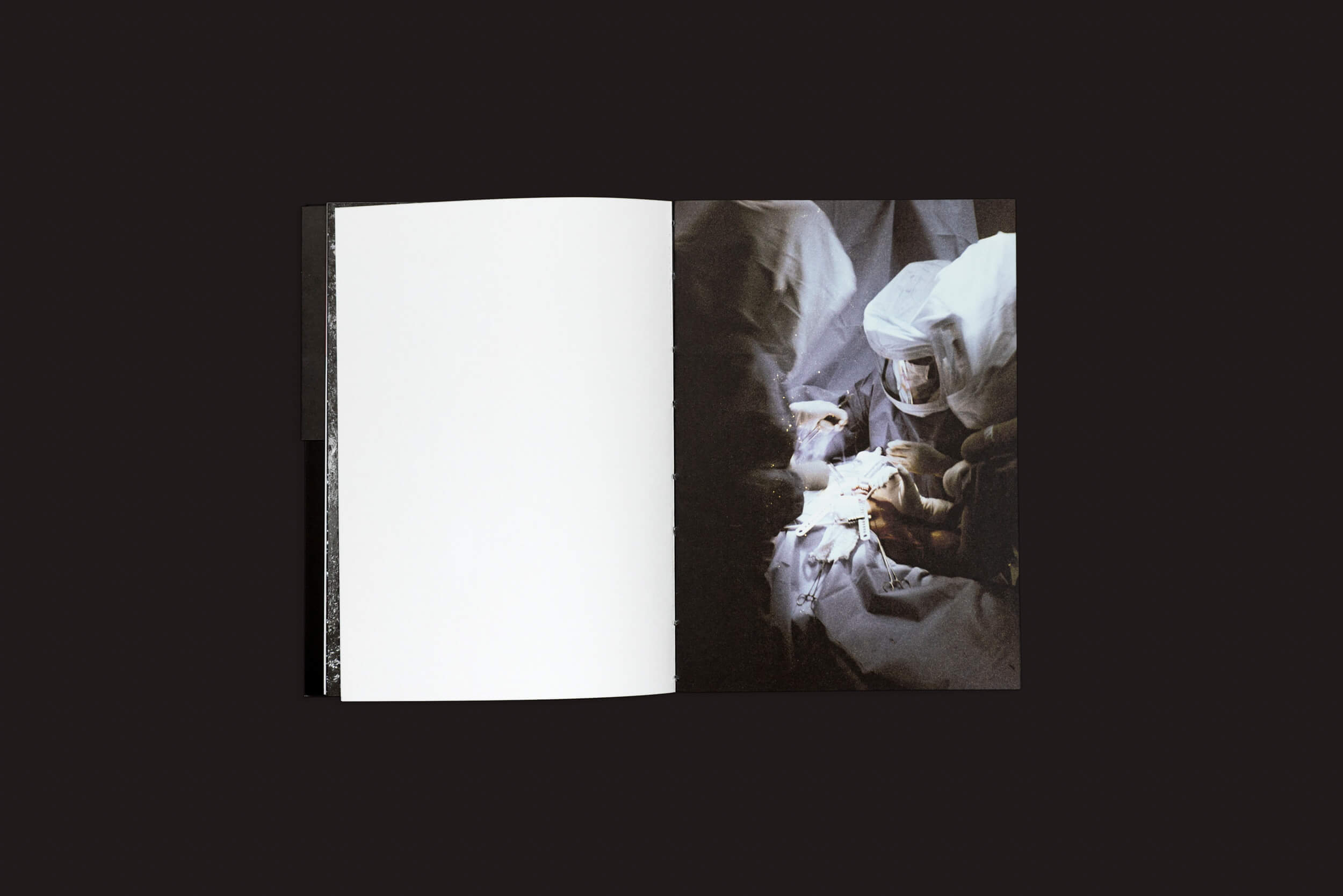 Um livro aberto intitulado Claudio Albarrán Briso: La herida del hombre, da SED Editorial, está sobre uma superfície escura, mostrando uma página esquerda em branco e a direita retratando cirurgiões em uniformes azuis realizando uma operação sob luzes brilhantes.