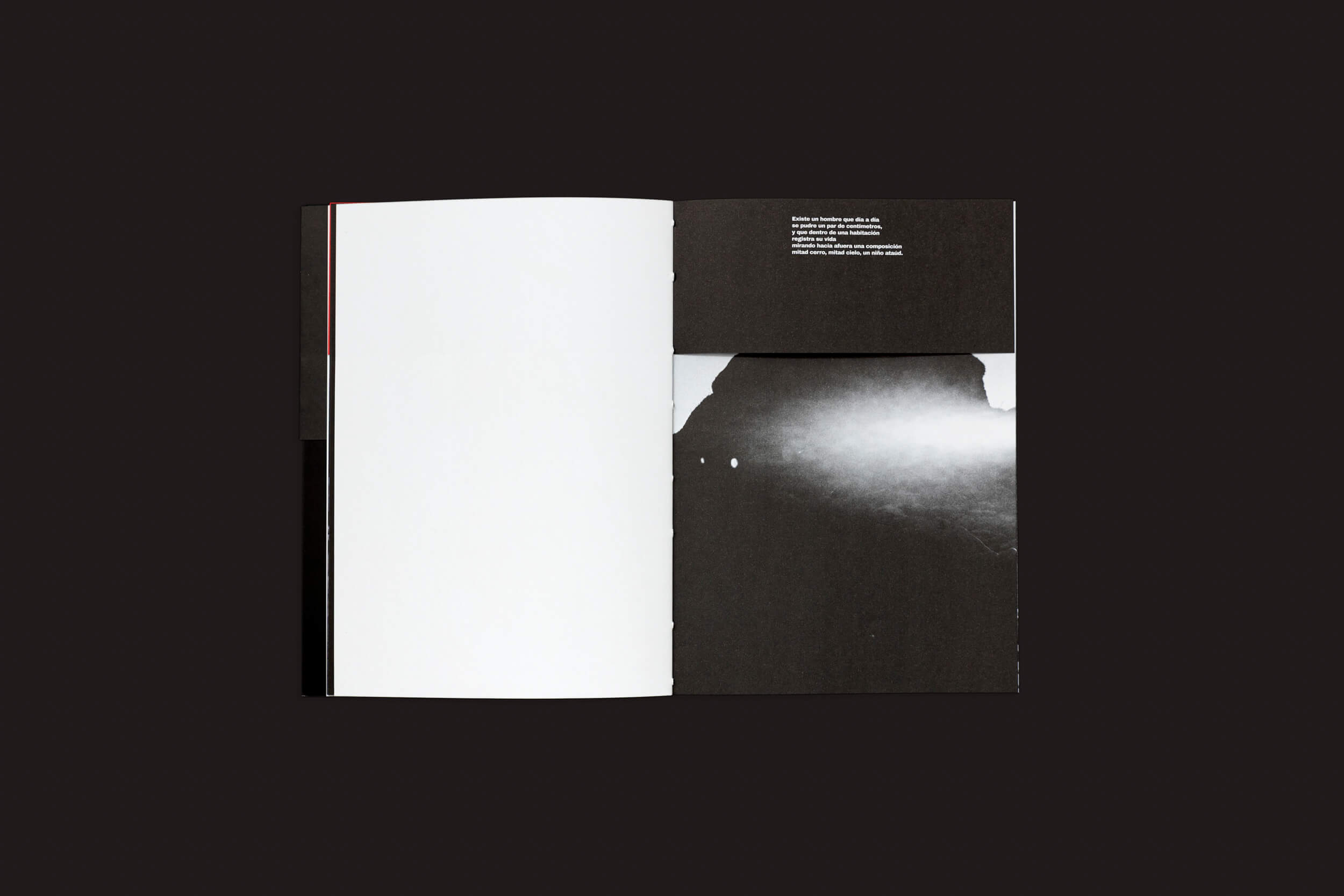 Sobre uma superfície escura está um livro aberto, Claudio Albarrán Briso: La herida del hombre da SED Editorial. A página da esquerda está em branco; a da direita apresenta uma imagem abstrata em preto e branco que lembra encontros — um aceno artístico para encontros simbólicos, com um pequeno texto branco no topo.