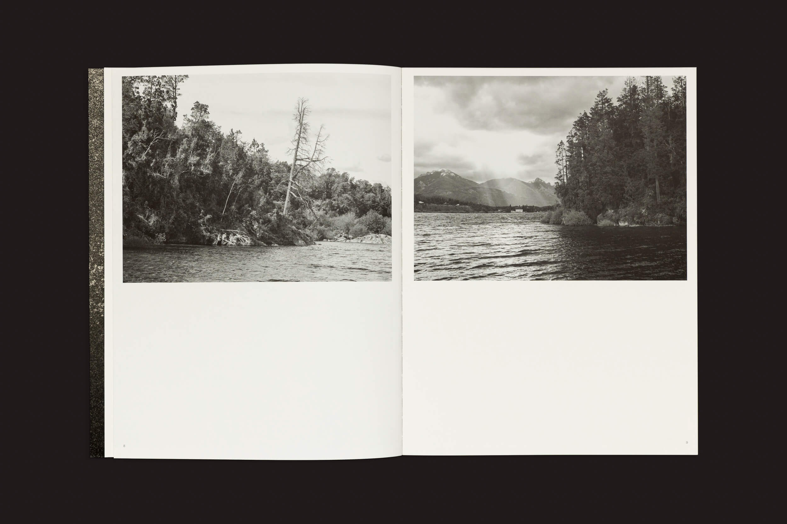 O livro aberto Pablo Cabado: Little Suns on Earth de The Eriskay Connection mostra um corpo de água perto de Ilha Huemul e árvores na página esquerda, enquanto a página direita apresenta um lago com montanhas distantes e uma floresta. Ambas as fotos em preto e branco têm um fundo escuro, capturando o estilo temperamental de Cabado.