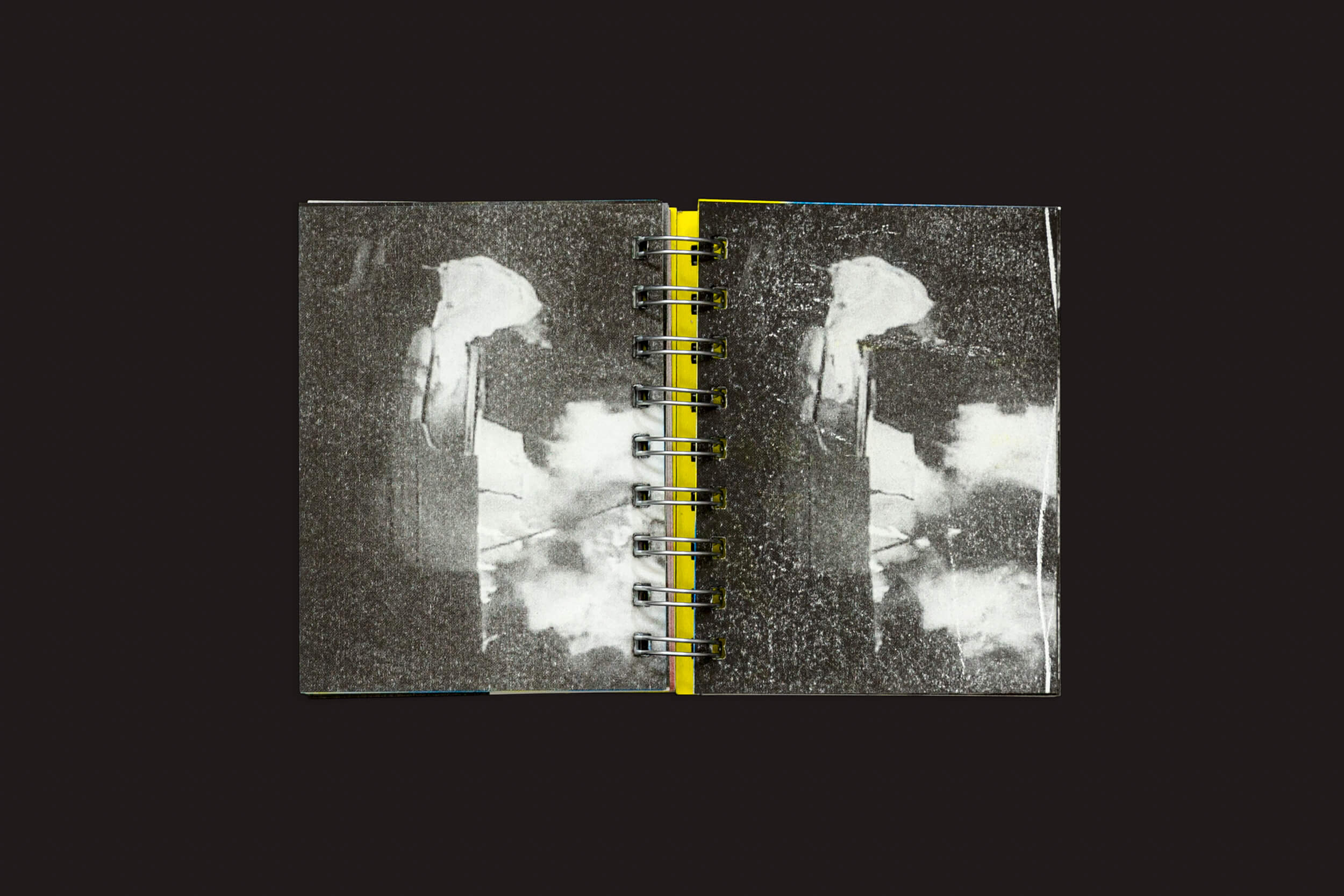 O Manifiesto Antiético de Gonzalo Golpe e Marina Meyer, da SED Editorial, é um caderno espiral aberto que exibe imagens abstratas em preto e branco com formas verticais e formas semelhantes a nuvens. Suas páginas texturizadas contrastam lindamente com um fundo preto sólido.