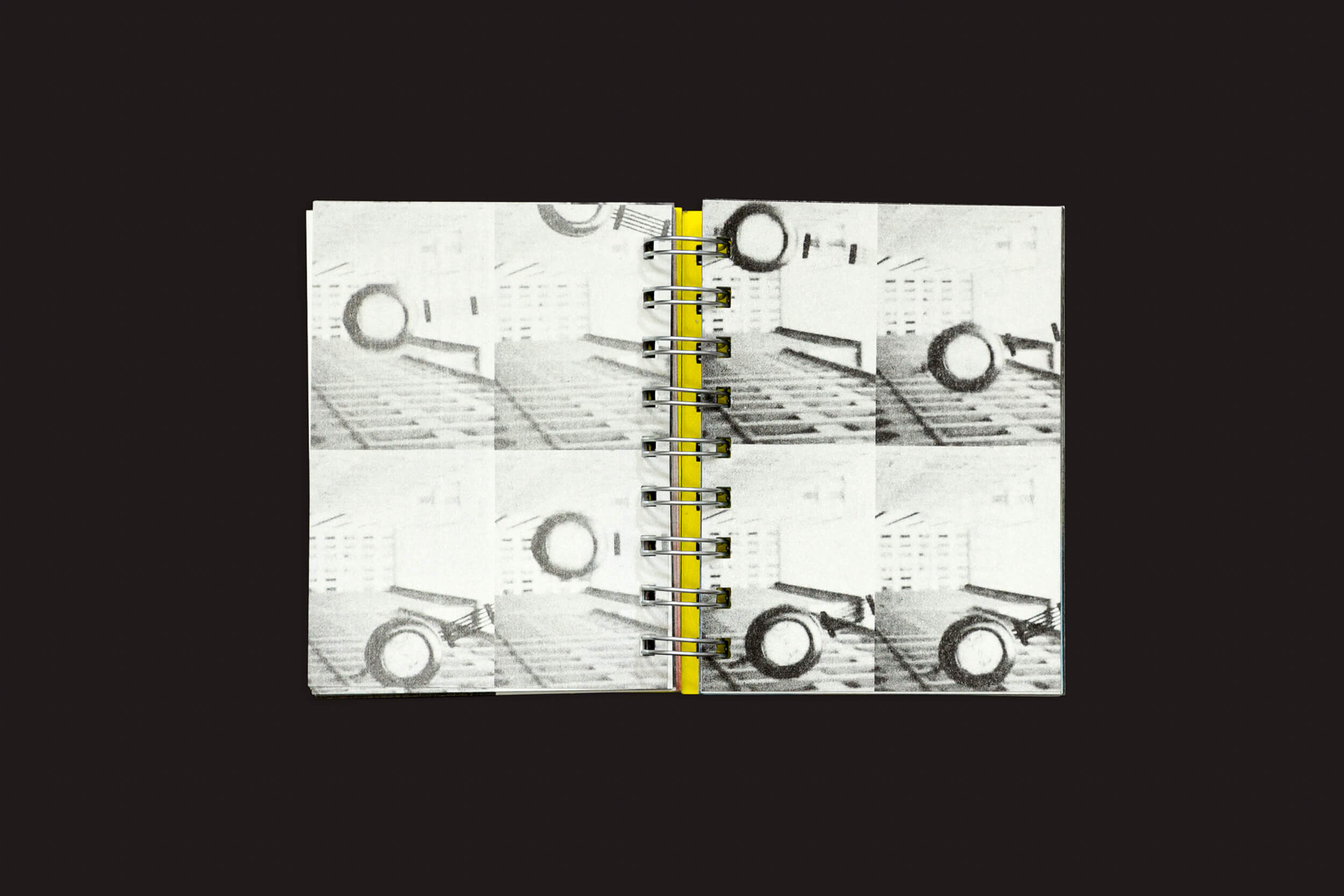 O caderno espiral Manifiesto Antiético da SED Editorial exibe imagens gráficas industriais em preto e branco com impressões repetitivas. Uma linha vertical amarela marcante acentua a encadernação central, capturando perfeitamente a essência do meio editorial.