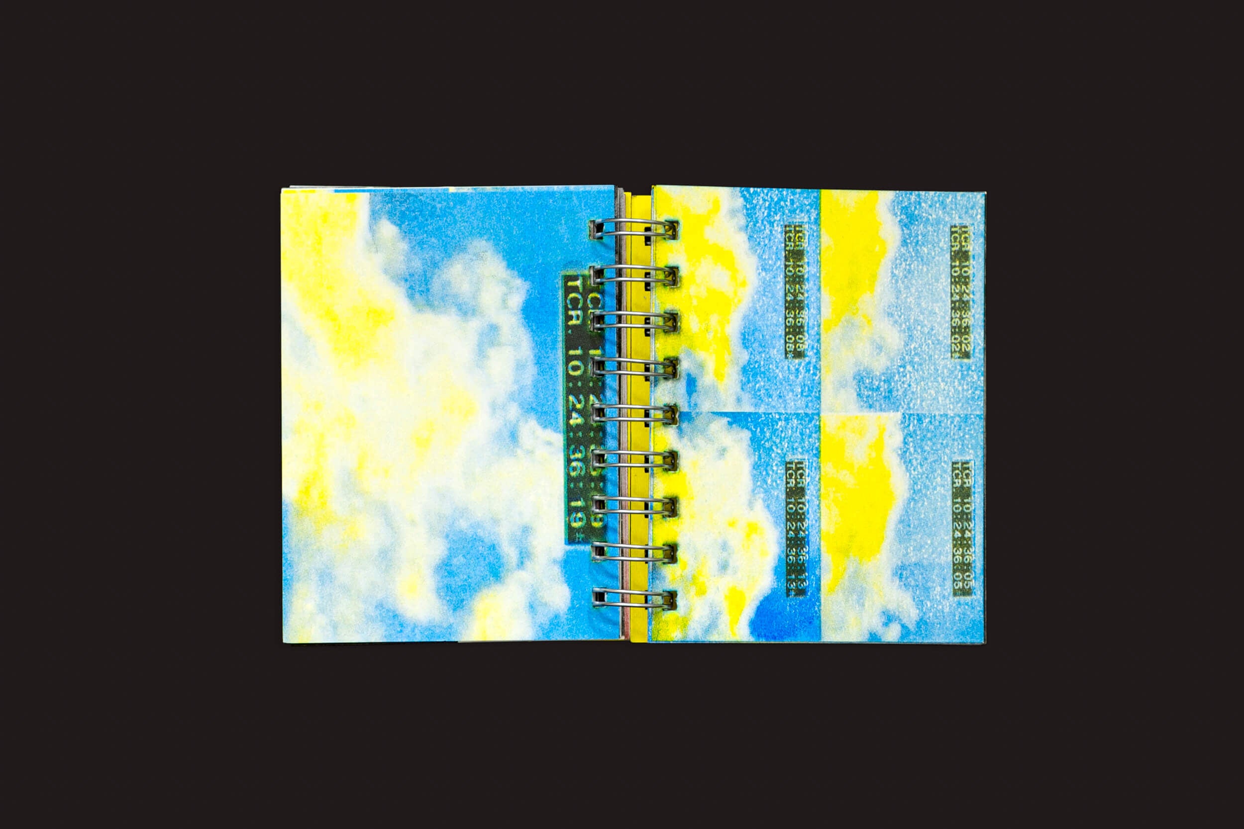 Um caderno aberto com espiral sobre um fundo preto revela céus e nuvens vibrantes com retângulos cheios de texto espalhados por ambas as páginas, exibindo o ensaio visual de Gonzalo Golpe e Marina Meyer: Manifesto Antiético da SED Editorial.