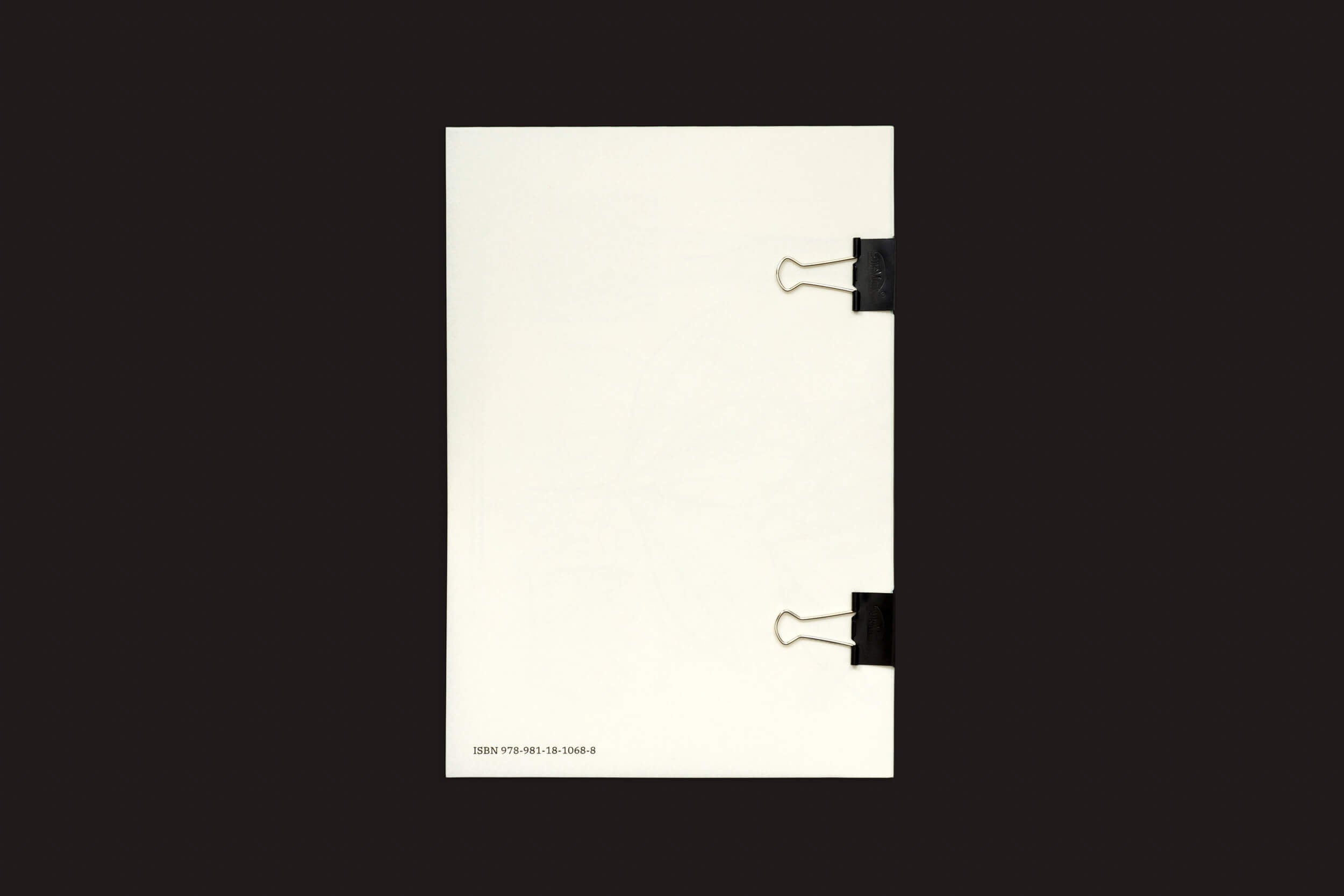 Uma pilha de Loh Xiang Yun: Microscopic Images da Temporary Press é mantida unida por dois clipes de fichário pretos à direita, colocados contra um fundo escuro. O canto inferior esquerdo dos papéis apresenta texto pequeno e números.