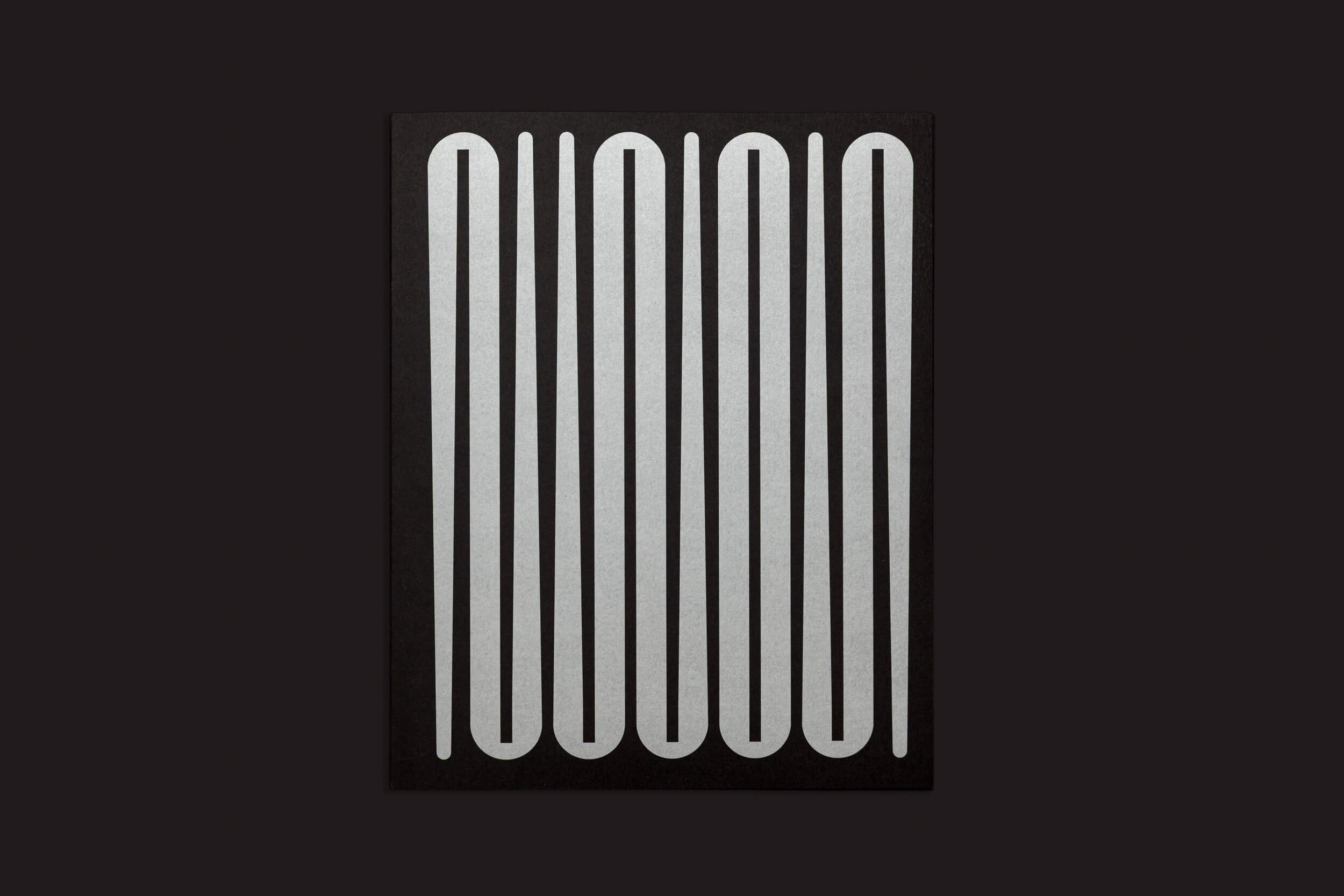 O Ezio D'Agostino: NEOS da Skinnerboox apresenta uma capa preta com ovais prateados verticais e alongados. Este conjunto abstrato evoca o tema da mineração de asteroides, contrastando fortemente com o fundo escuro, criando um visual inspirado em recursos espaciais.