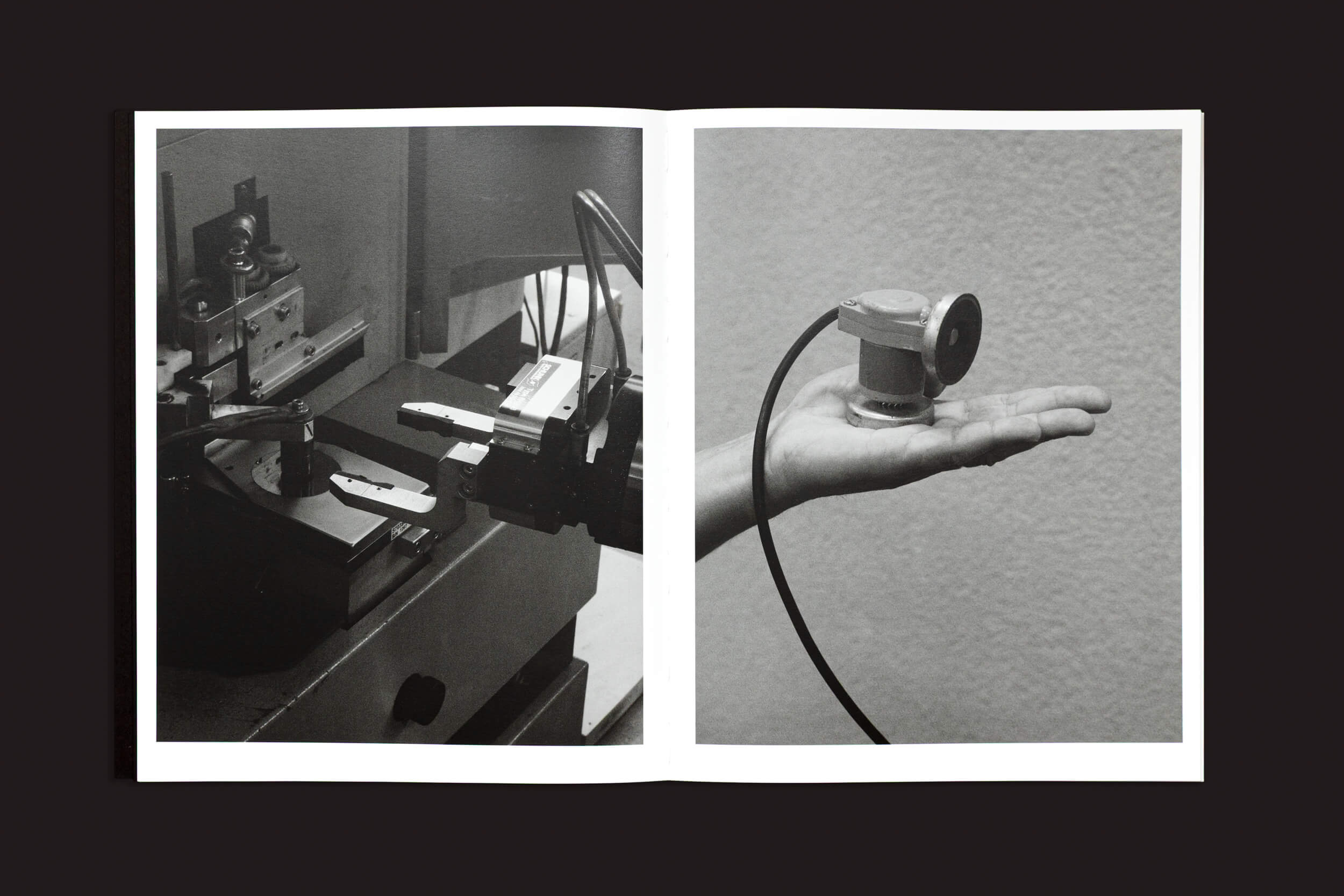 Uma imagem em preto e branco de "Ezio D'Agostino: NEOS", de Skinnerboox, mostra maquinário industrial na página da esquerda, simbolizando o futuro da mineração de asteroides. À direita, uma mão segura um pequeno dispositivo com um cabo contra um fundo texturizado.