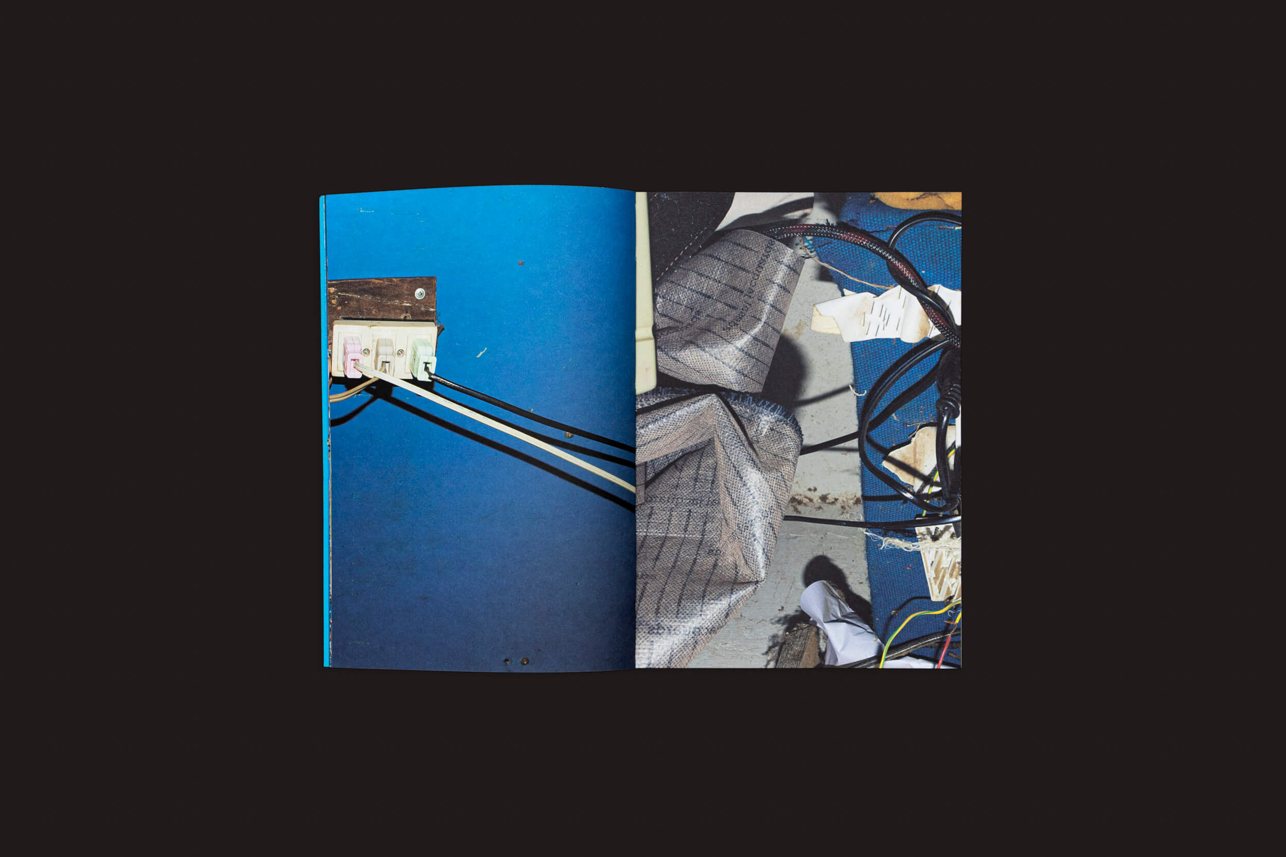 Abrir Henrik Malmström: NÃO por SED Editorial em um fundo preto. A página da esquerda mostra fotografia urbana com uma parede azul e fios conectados por interruptores; a da direita apresenta intervenções elétricas com feixes de fios e um objeto texturizado em cinza.