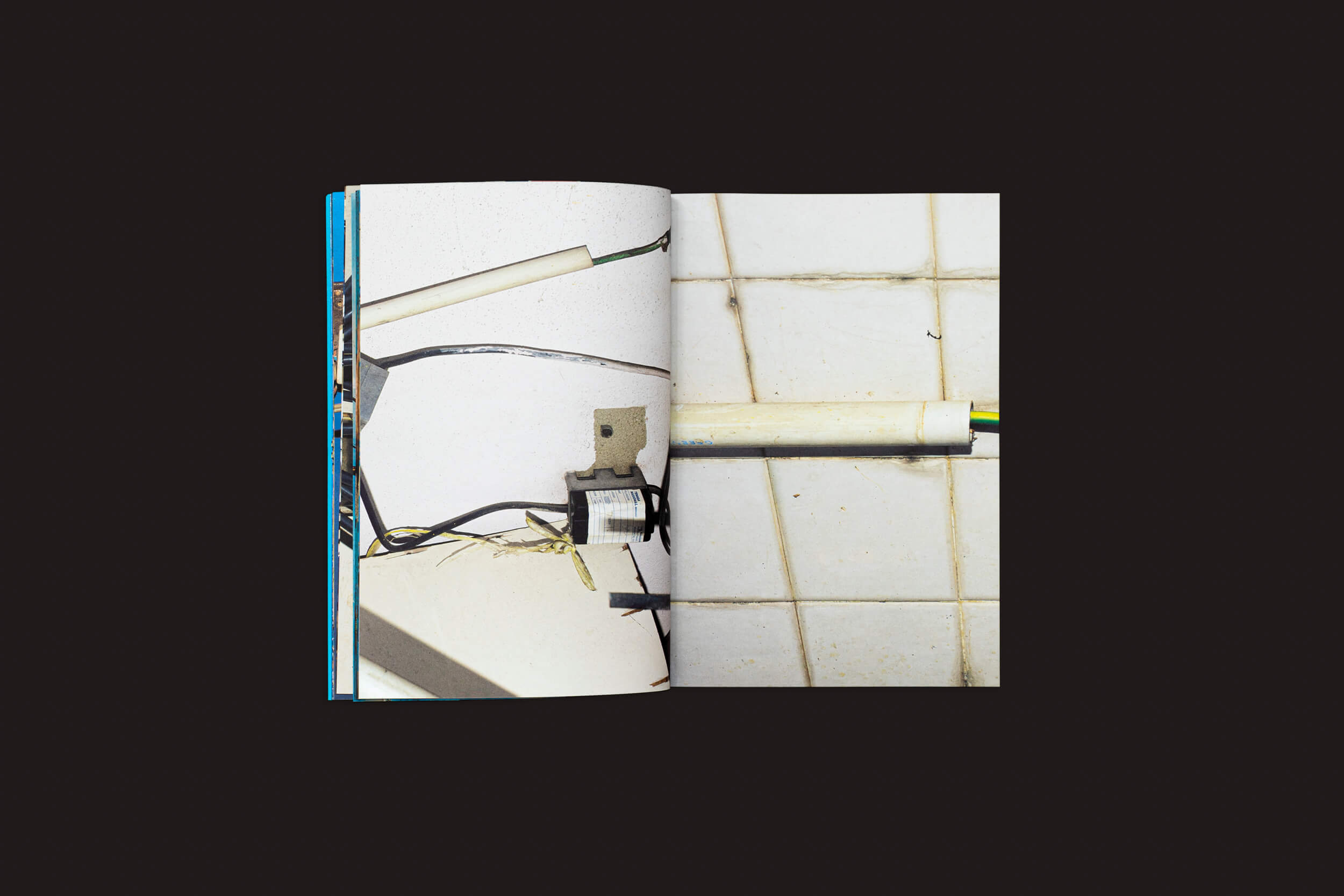 O livro Henrik Malmström: NÃO da SED Editorial traz fotos de intervenções elétricas e fiação exposta contra paredes de azulejos brancos, criando um contraste vívido com seu fundo preto sólido, destacando as imagens da fotografia urbana.