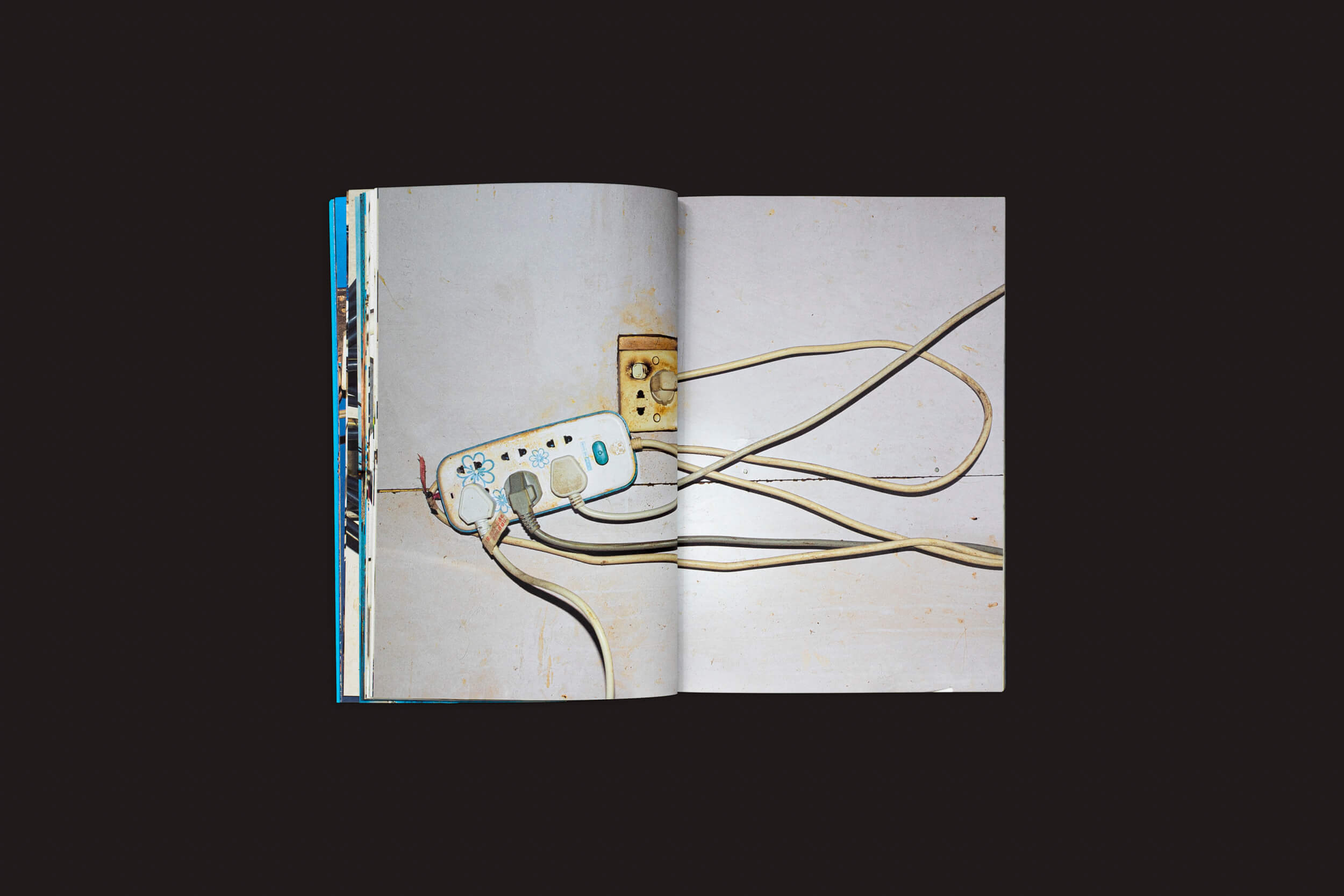 Exibida em Henrik Malmström: NO da SED Editorial, uma foto urbana de um filtro de linha com vários plugues contra um fundo escuro mostra a complexidade das conexões elétricas modernas.