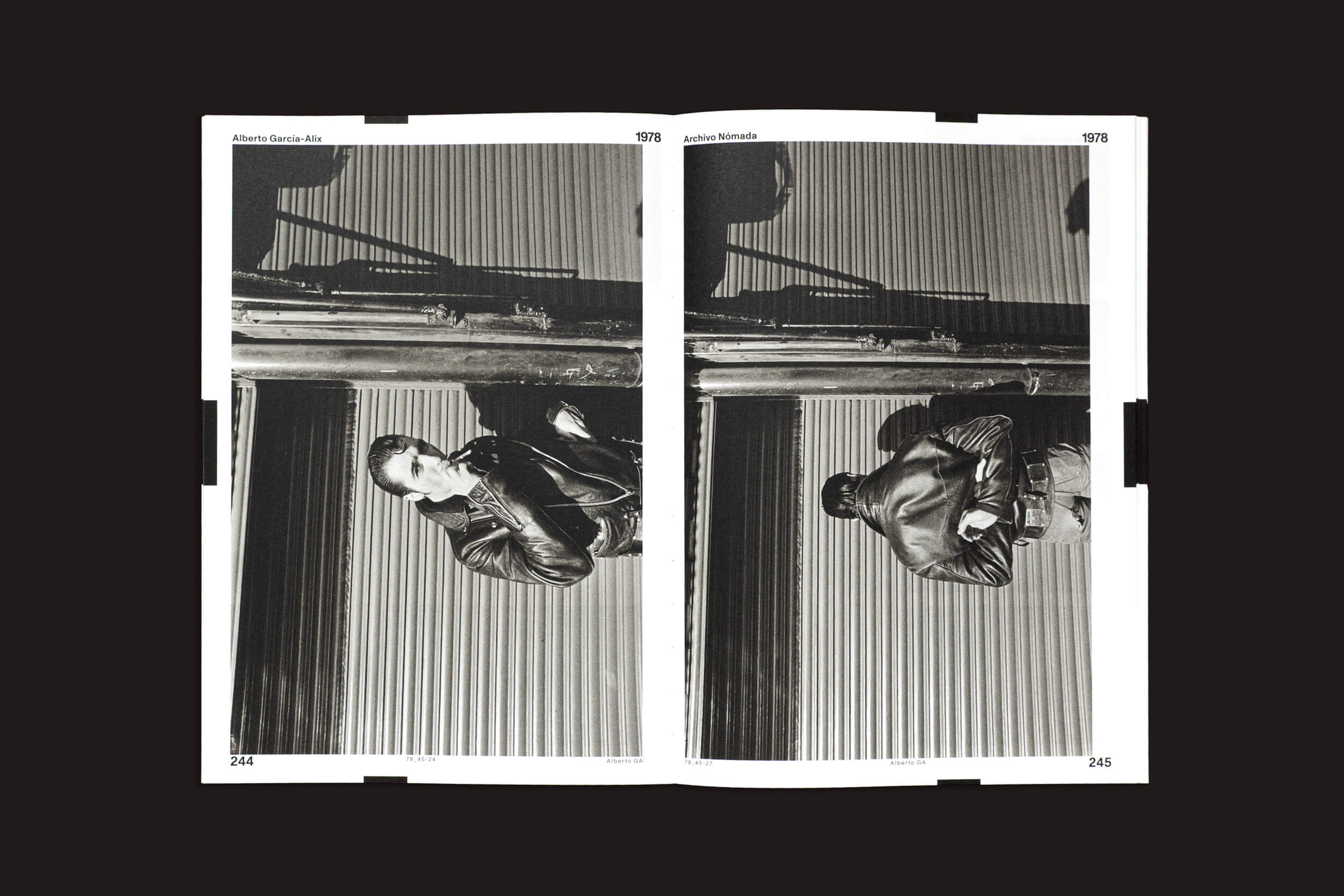 Um livro aberto de Cabeza de Chorlito, com a obra "Alberto García-Alix: Arquivo Nômade 01", exibe fotos em preto e branco nas páginas 244 e 245. À esquerda, uma pessoa vestida de couro perto de um prédio é espelhada de cabeça para baixo à direita, contra uma superfície escura que evoca um amplo arquivo fotográfico.