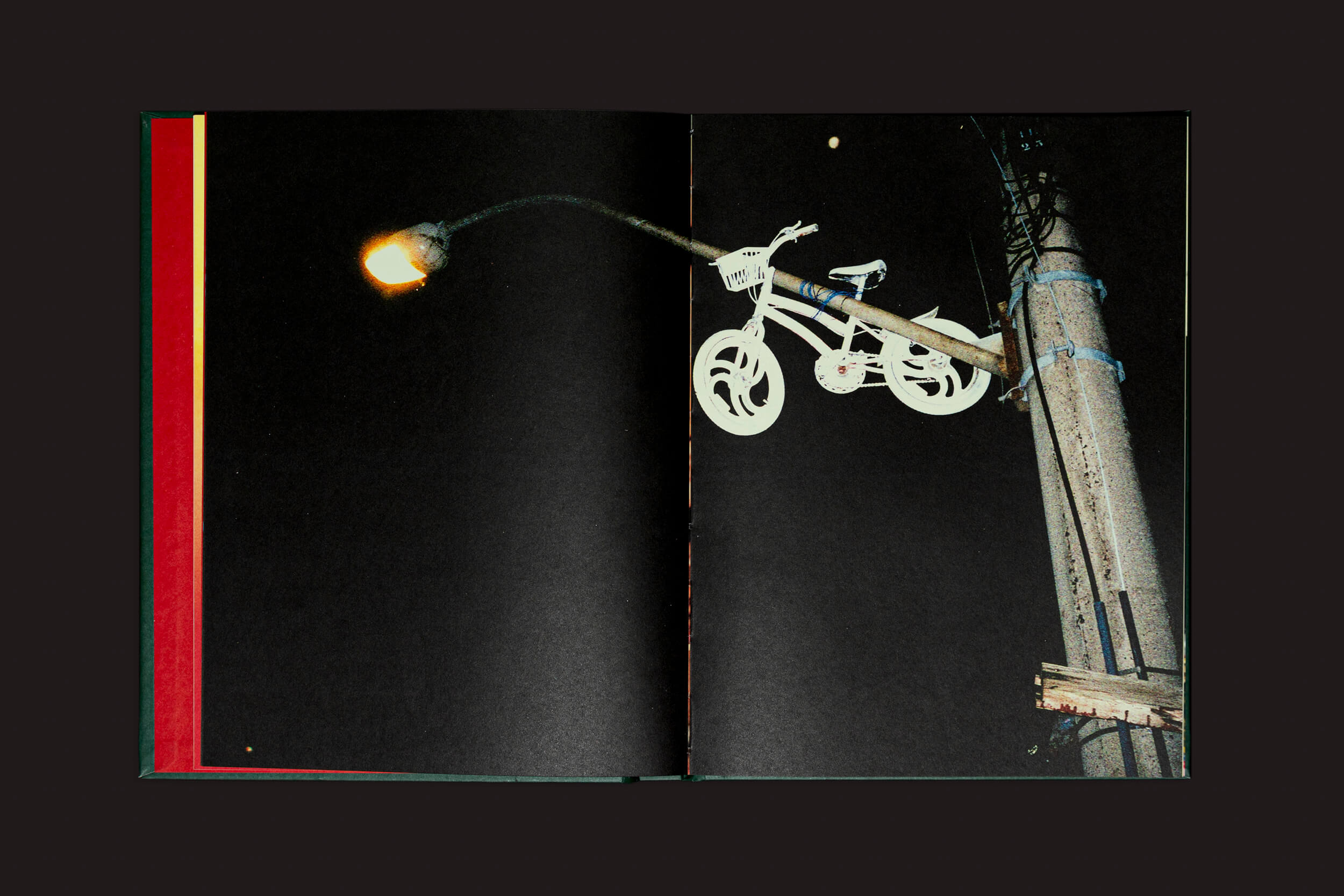 O fotolivro Erick Peres: O choro pode durar uma noite, mas a alegria vem pela manhã de Selo Turvo revela uma cena de rua escura onde um poste aceso segura uma bicicleta branca no braço contra o céu noturno, evocando profunda memória familiar.