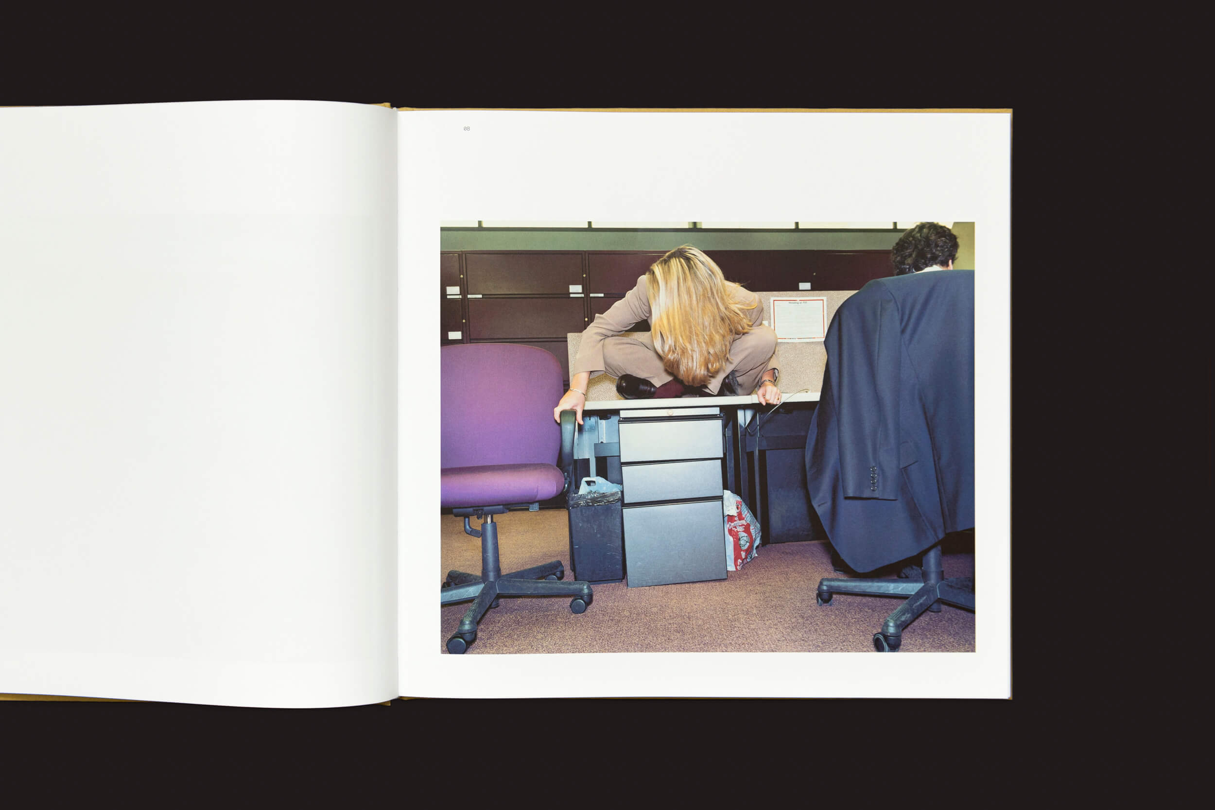 Em um escritório que evoca uma cena de Lars Tunbjörk, uma pessoa se inclina sobre sua mesa com a cabeça no encosto da cadeira. O espaço, preenchido com várias cadeiras e um arquivo, captura a essência das organizações tradicionais em meio à tendência do trabalho remoto. (Produto: Lars Tunbjörk: Office / LA Office por Loose Joints).