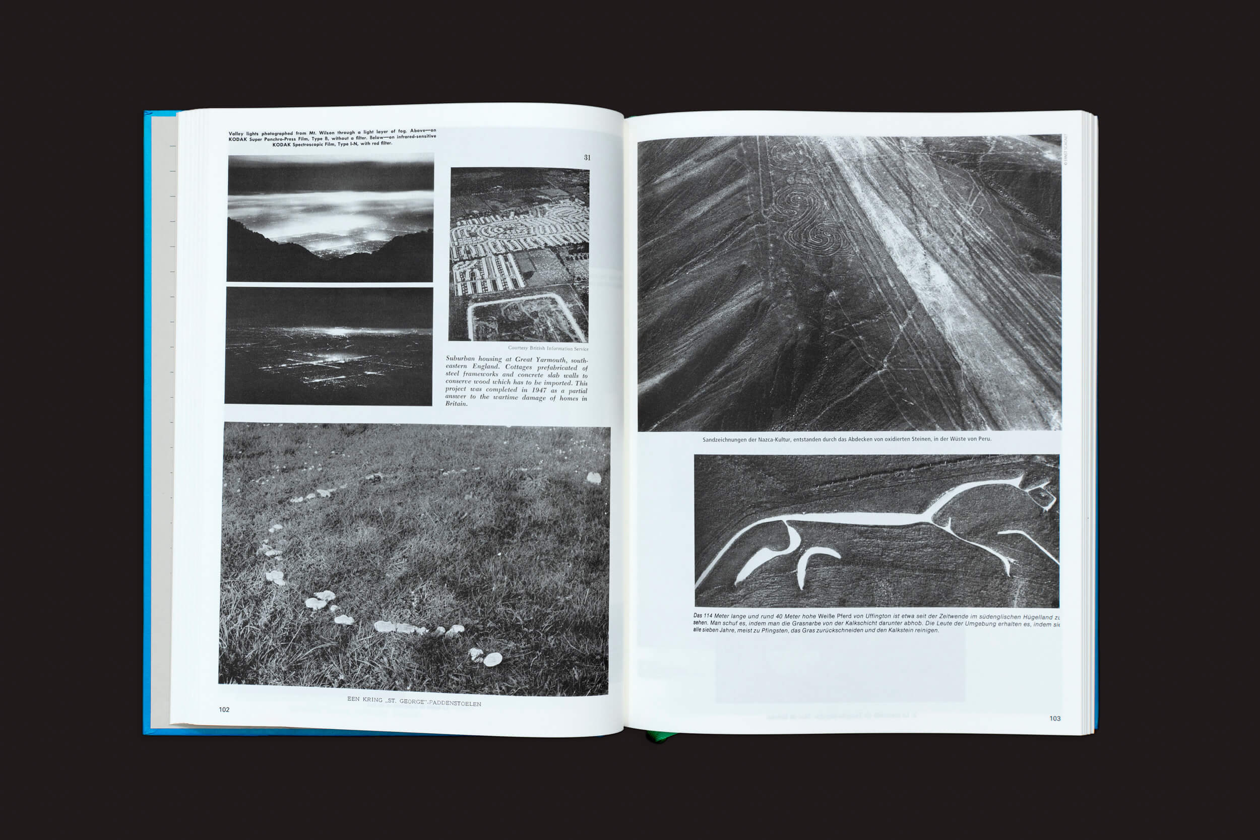 O livro de fotografia aérea, estilizado como Parallel Encyclopedia 1 de Batia Suter da Roma Publications, exibe imagens icônicas de paisagens em preto e branco, incluindo campos e um geoglifo de cavalo. O texto descritivo fornece contexto contra um fundo escuro.