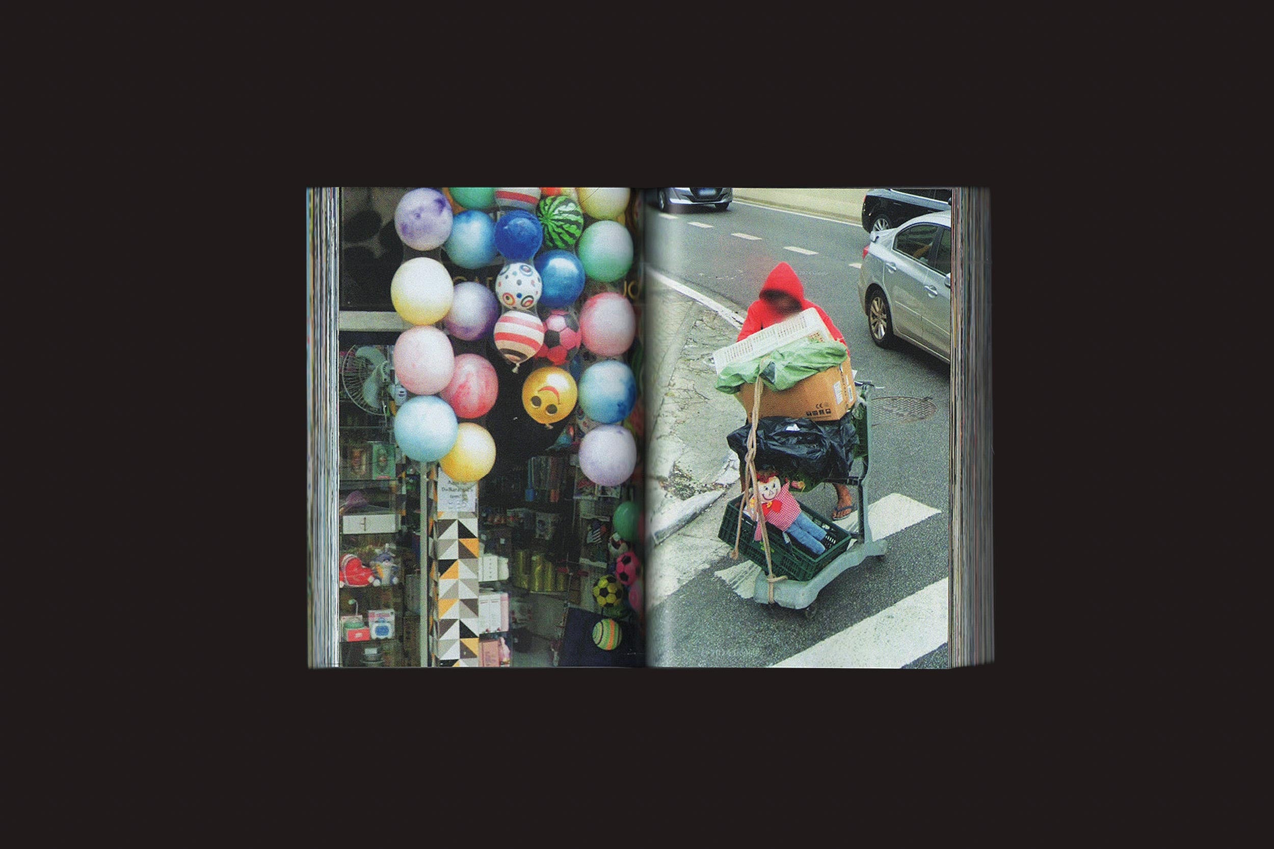 Em "Romeu Silva: Passantes", da zero-Edições, um livro aberto mostra uma vitrine animada com balões e brinquedos em uma página e uma pessoa empurrando um carrinho pela movimentada São Paulo na outra, capturando a vida urbana.