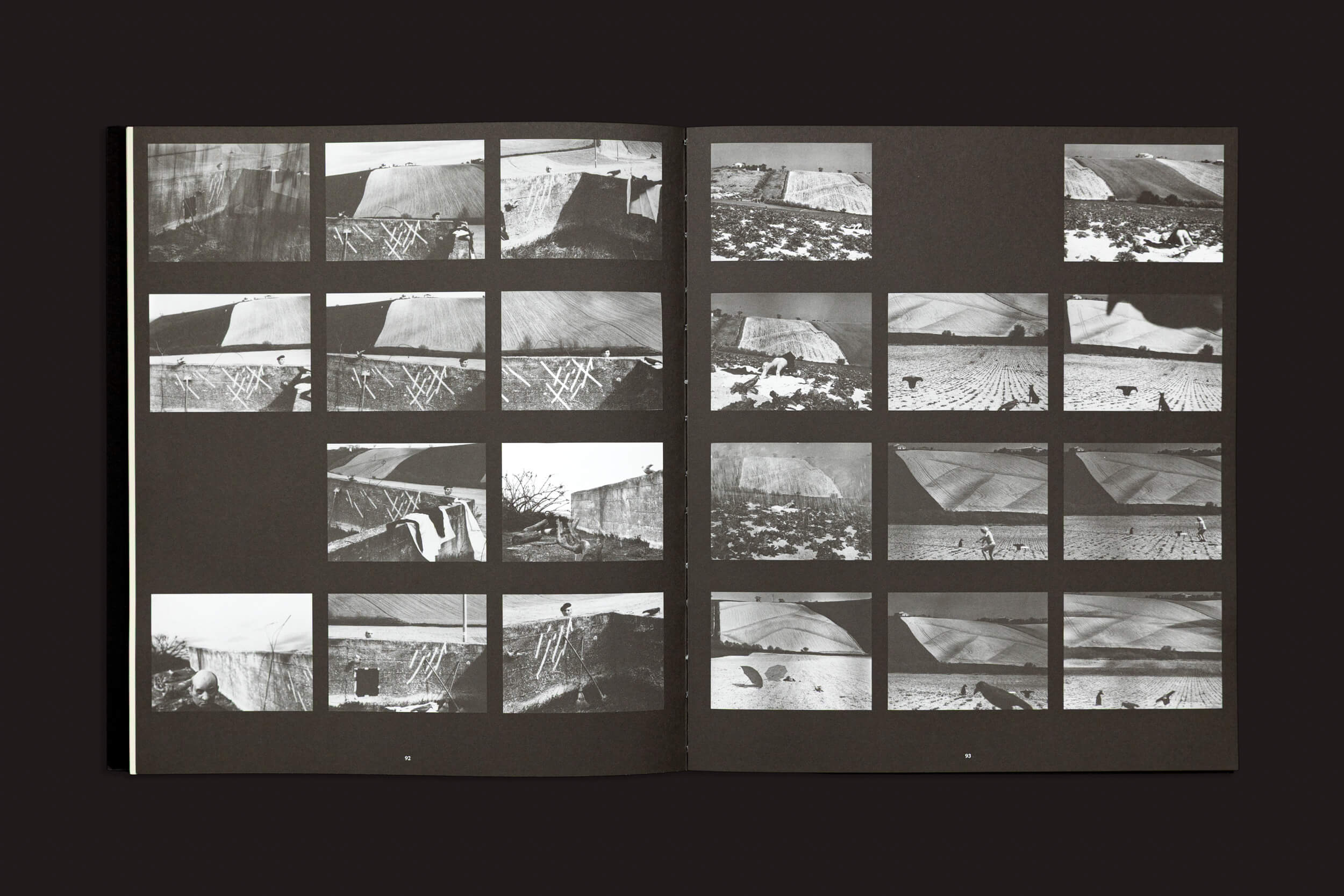 O livro aberto "Mario Giacomelli: Questo ricordo lo vorrei raccontare", de Skinnerboox, revela duas páginas exibindo fotografias em preto e branco de grandes instalações de arte com tecidos cobrindo paisagens, ecoando estilos composicionais contra um fundo escuro.