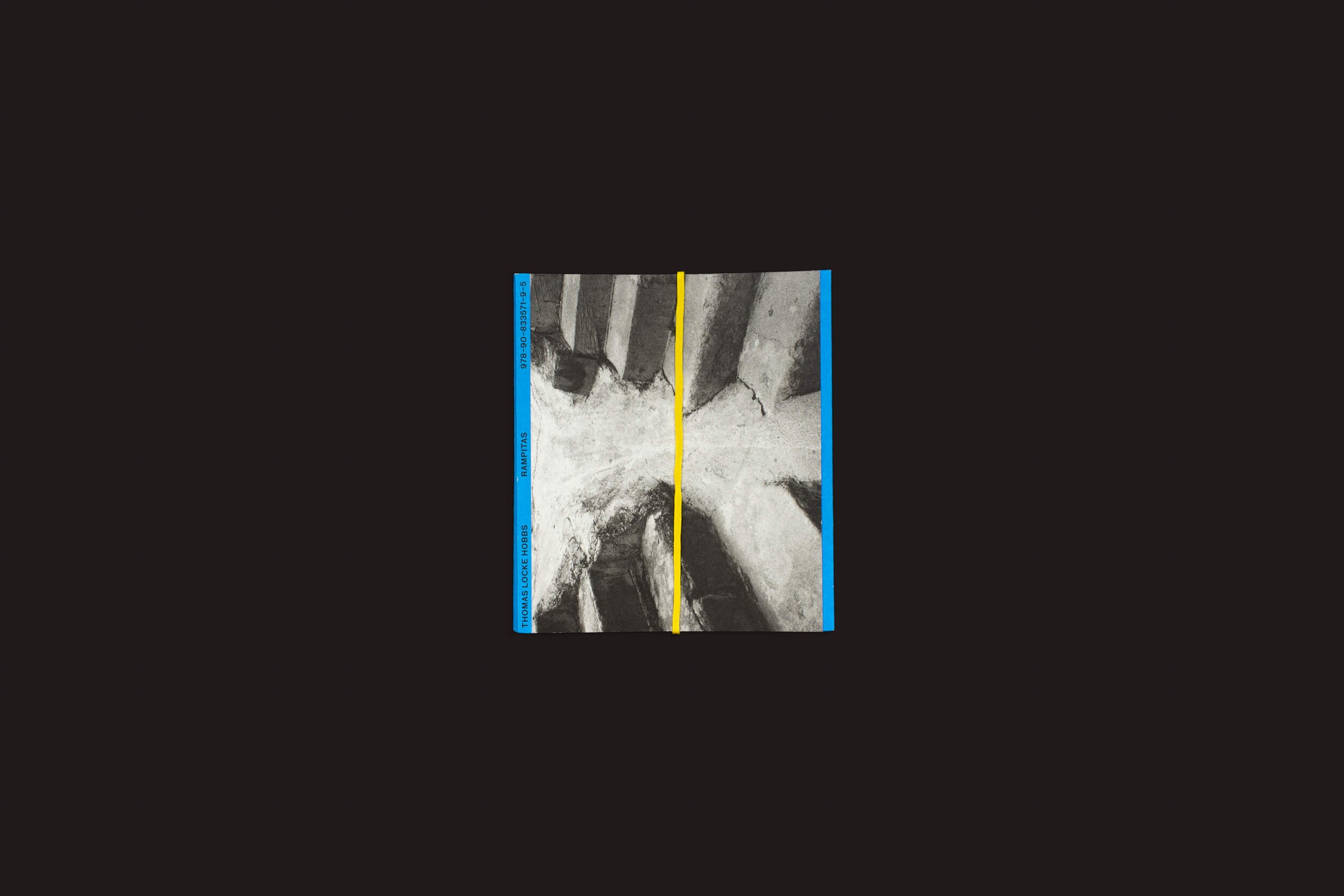 Thomas Locke Hobbs: Rampitas de The Eriskay Connection exibe arte geométrica abstrata com uma linha vertical amarela e padrões texturizados em preto e branco. Bordas azuis emolduram o design, tudo em um fundo preto simples, evocando o brutalismo popular.