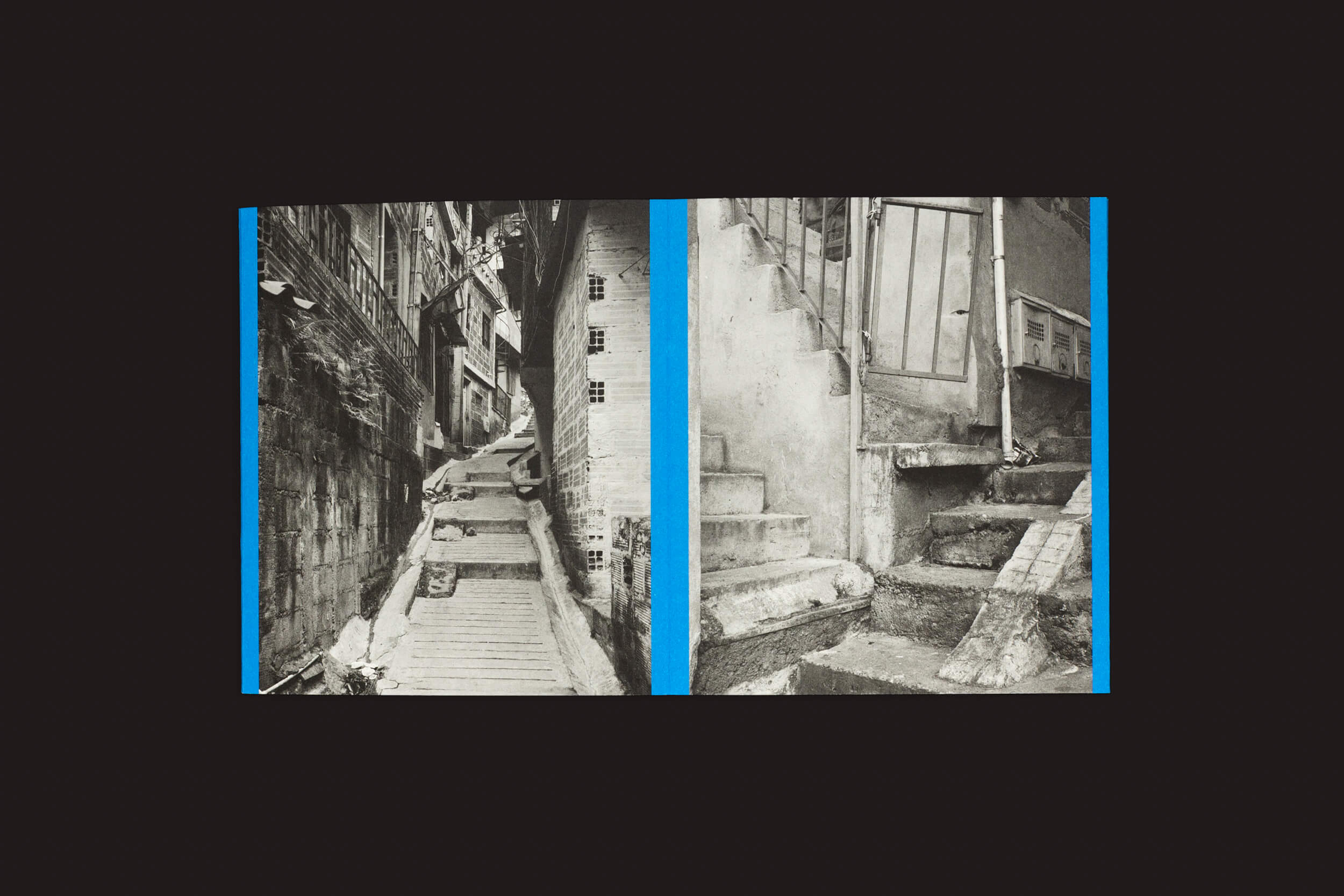 Uma imagem dividida apresenta fotos em preto e branco com bordas azuis brilhantes. Esquerda: um beco estreito com degraus irregulares entre prédios altos refletindo o brutalismo popular. Direita: degraus de pedra fragmentados levando a uma porta de metal, que lembram rampas esculturais — ambos de Rampitas de Thomas Locke Hobbs, de The Eriskay Connection.