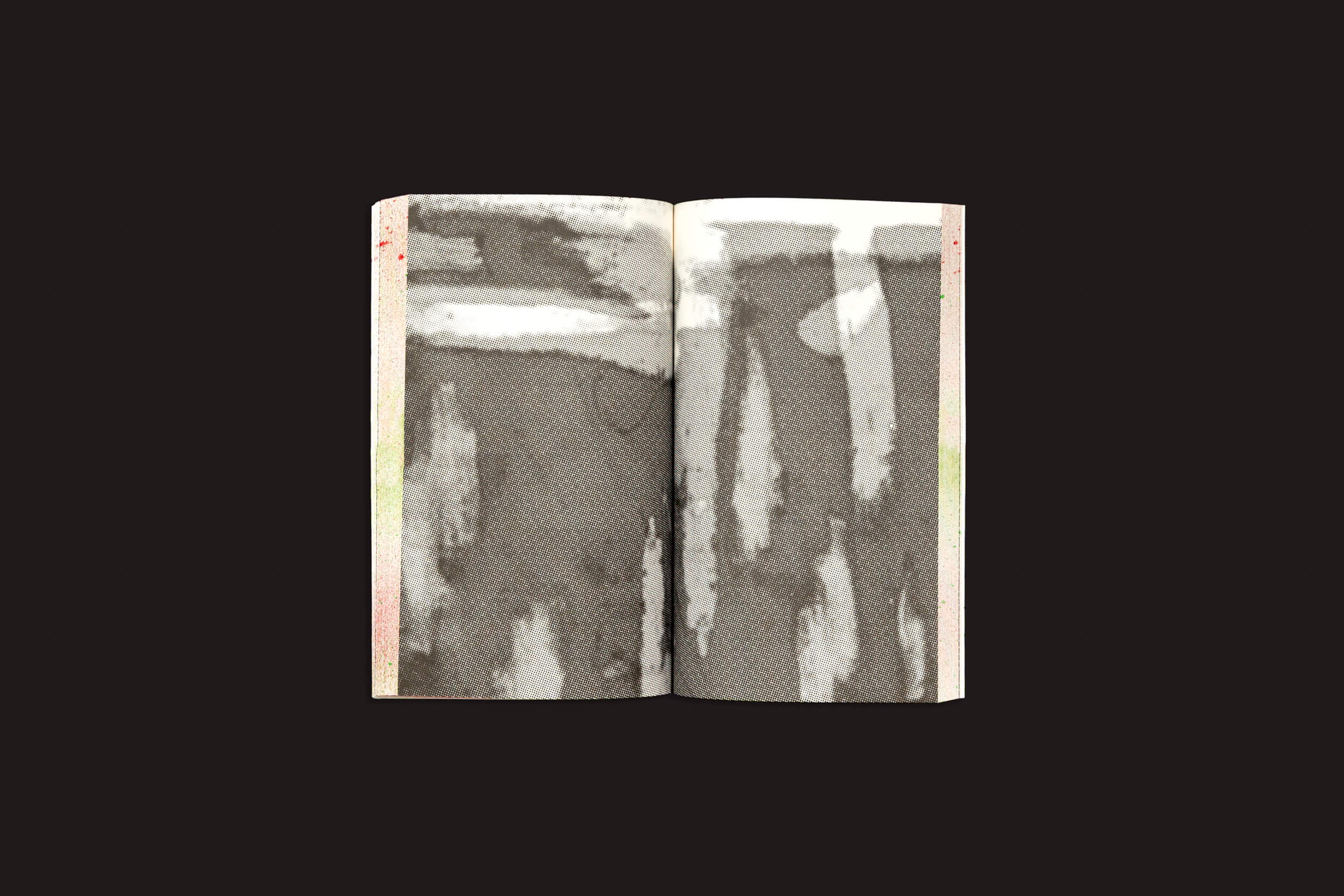 Um livro aberto revela manchas e listras abstratas em tons de cinza, semelhantes a aquarela, em suas páginas, personificando "Reworlding Ramallah - Short Science Fiction Stories from Palestine", de Onomatopee. O fundo preto sólido acentua os padrões artísticos indistintos que narram histórias que se desenrolam entre fronteiras.