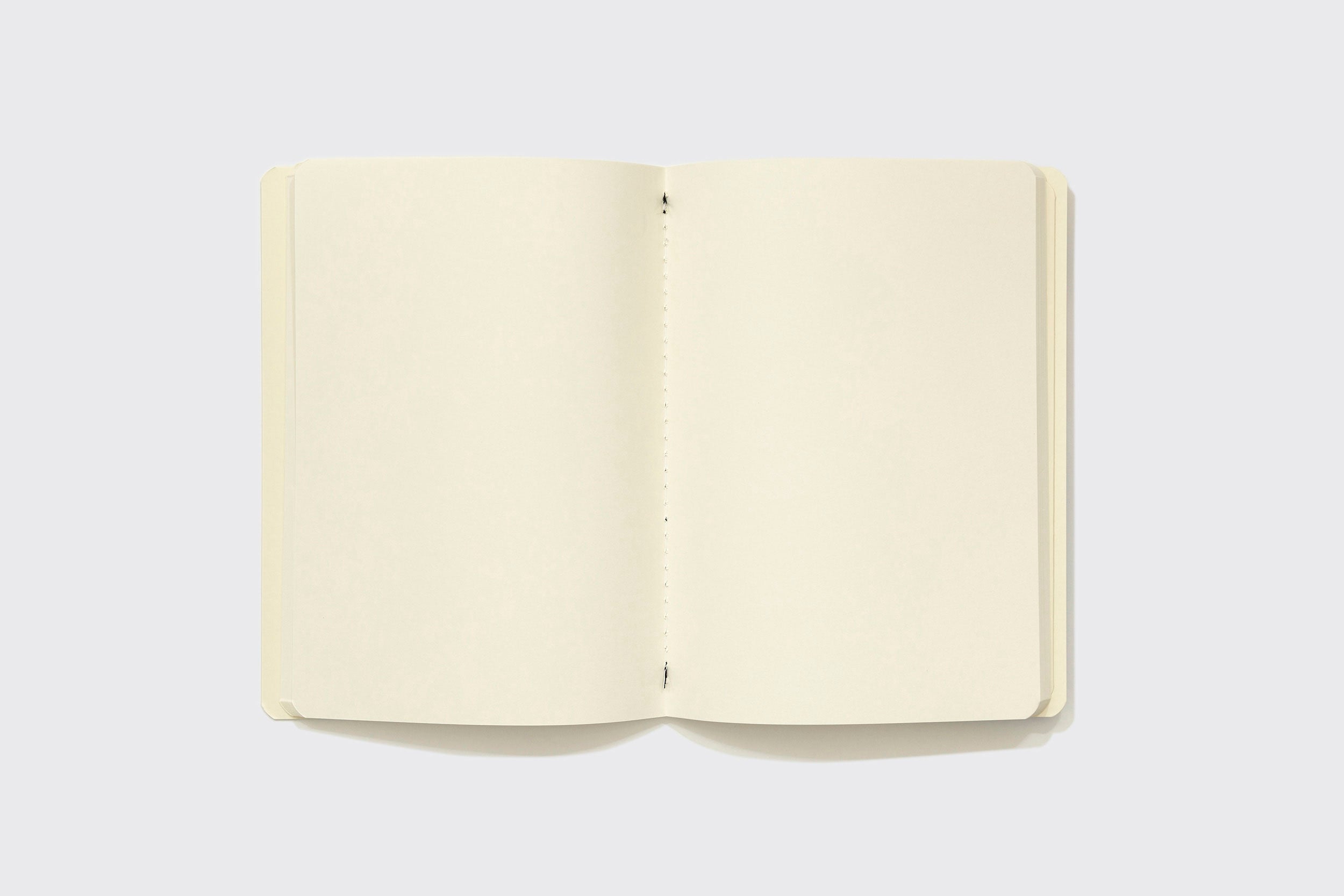 O Sketchbook XLarge da Schizzibooks, feito à mão no Brasil, possui páginas creme lisas e está novo. Ele está aberto sobre um fundo cinza-claro.