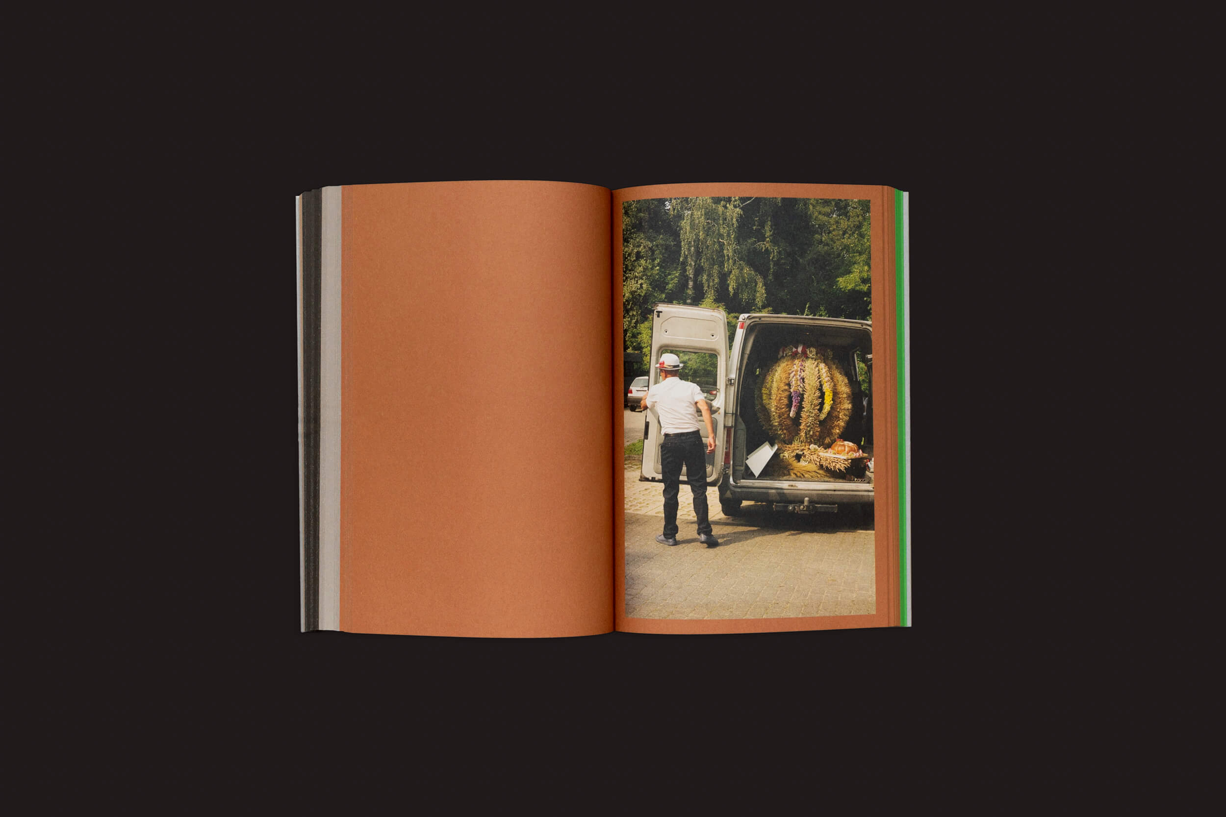 Um livro aberto intitulado Seasonal Neighbours: Seasonal Matters Rural Relations de Onomatopee exibe uma foto de um homem ao lado de uma van aberta com um grande cacto, em contraste com uma vegetação luxuriante, incorporando práticas artísticas e relações rurais. As imagens vívidas contrastam com as páginas marrons de forma impressionante.