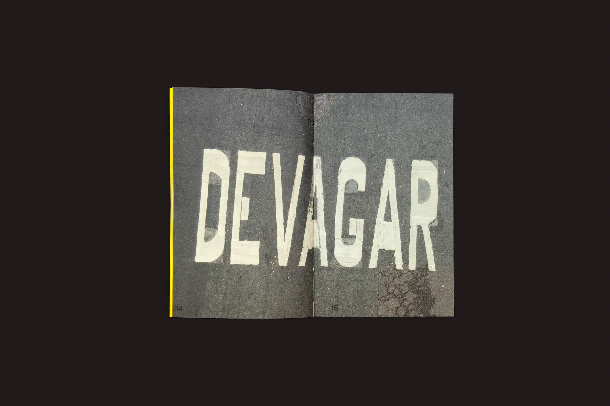 Uma página do livro Ermãos Monjon: Sinais/Sinais, da Livros Fantasma, exibe uma foto com DEVAGAR em letras brancas em negrito sobre asfalto escuro, destacando o estilo de linguagens gráficas de Ermãos Monjon contra um fundo preto simples.