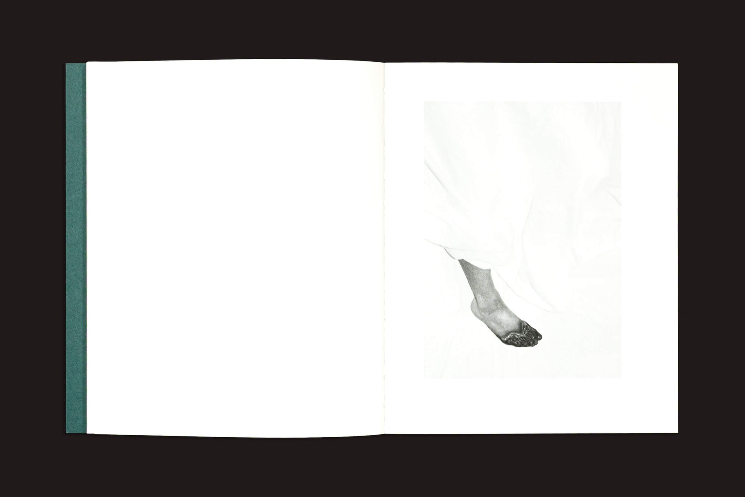 Um livro aberto sobre uma superfície escura mostra uma página em branco à esquerda e, à direita, uma foto em preto e branco de "Dylan Hausthor & Pia Paulina Guilmoth: Sleep Creek", de Void — um pé descalço envolto em tecido esvoaçante mistura documentário e ficção.