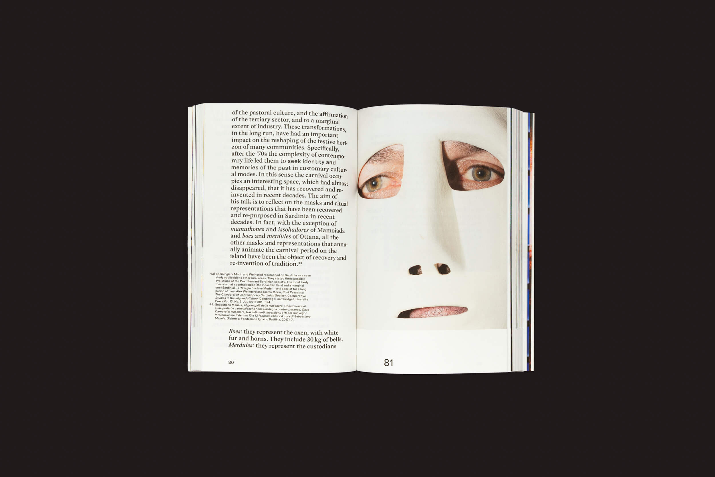 Nas páginas 80 e 81 de Some of you Killed Luisa de Valeria Cherchi, disponível em The Eriskay Connection, a página da esquerda exibe texto enquanto a da direita apresenta uma imagem de uma máscara branca com dois olhos. O livro é ambientado em um fundo escuro simples.