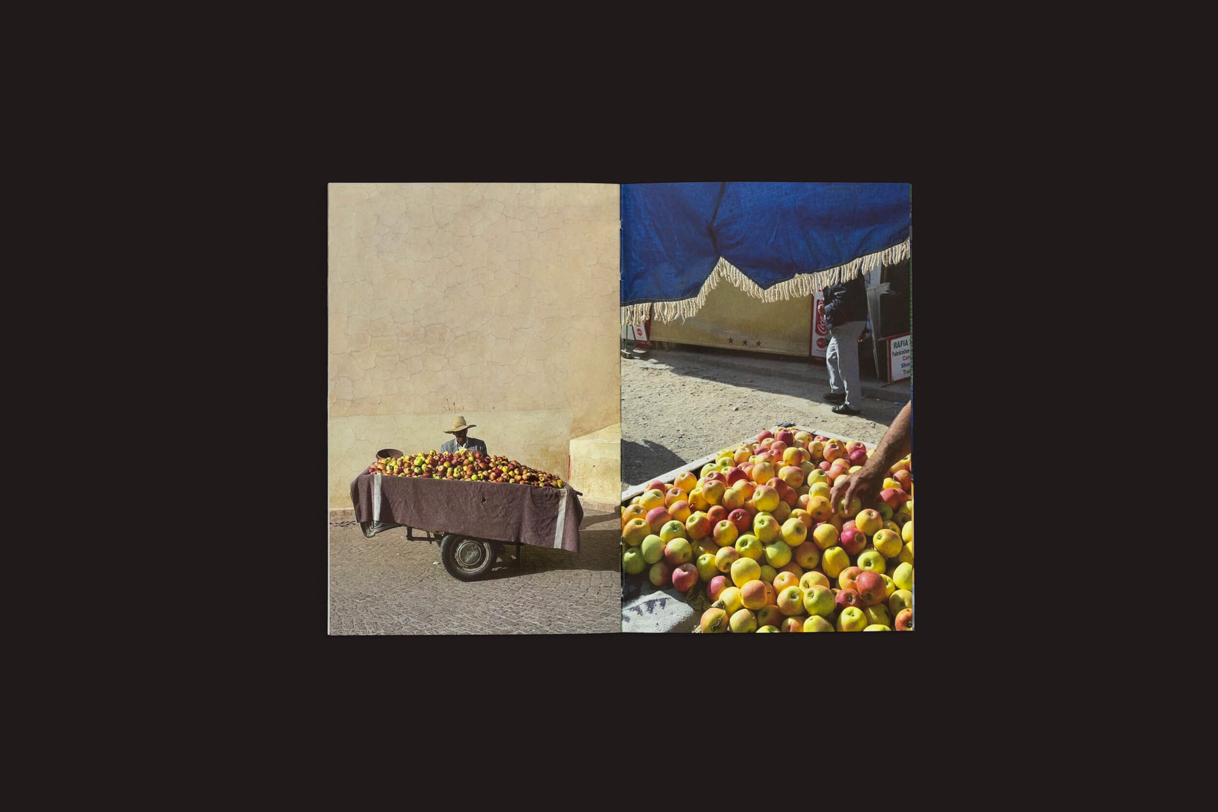 Em Sam Youkilis: Somewhere 2017-2023, de Loose Joints, uma imagem dividida mescla fotografias e obras observacionais: a esquerda mostra um carrinho de maçãs perto de uma parede com uma figura usando chapéu; a direita mostra uma mão pegando maçãs sob um dossel azul em um movimentado mercado de rua, capturando uma experiência humana íntima.