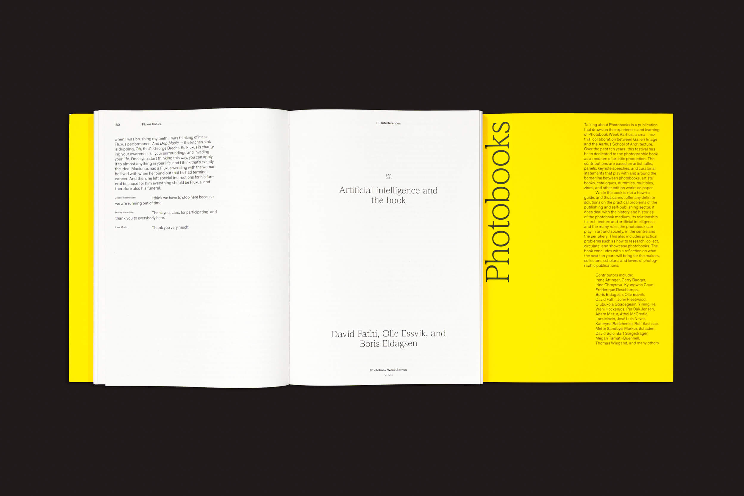 Um livro aberto da Fw:Books intitulado "Talking About Photobooks: Moritz Neumüller" apresenta uma capa preta e abas internas amarelas. A página da esquerda contém texto, enquanto a da direita diz "Inteligência artificial e o livro" com autores abaixo. A aba da direita tem texto amarelo. A lombada diz "Photobooks", refletindo o tema da história do fotolivro.