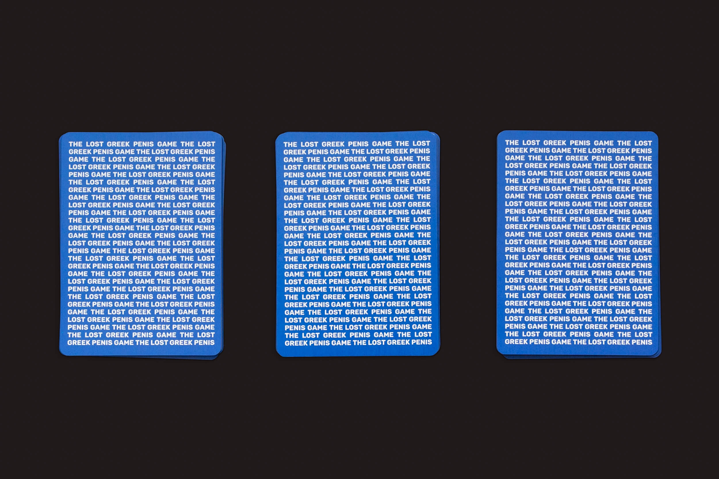 Três retângulos azuis com o texto branco repetido O JOGO DO PÊNIS GREGO PERDIDO da Fraglich Publishing evocam o espírito lúdico das estátuas gregas, misturando humor clássico com um toque moderno.