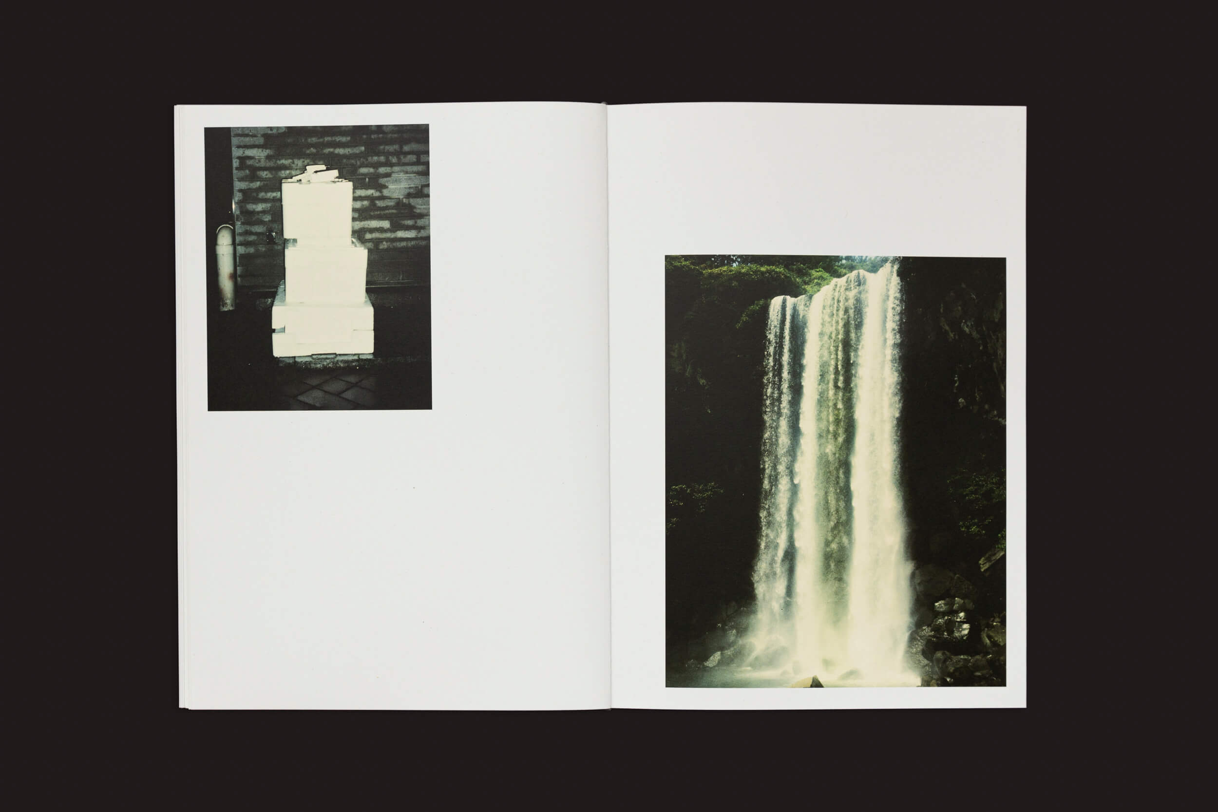 O livro aberto, Eduard Sánchez Ribot: Tierra, Camino, Fruto, da Handshake, convida você a uma viagem: a página da esquerda revela uma pilha de objetos em preto e branco contra uma parede; a da direita explode em cores, exibindo uma cachoeira em uma piscina cercada por vegetação exuberante — um verdadeiro caminho pelas páginas vívidas da natureza.