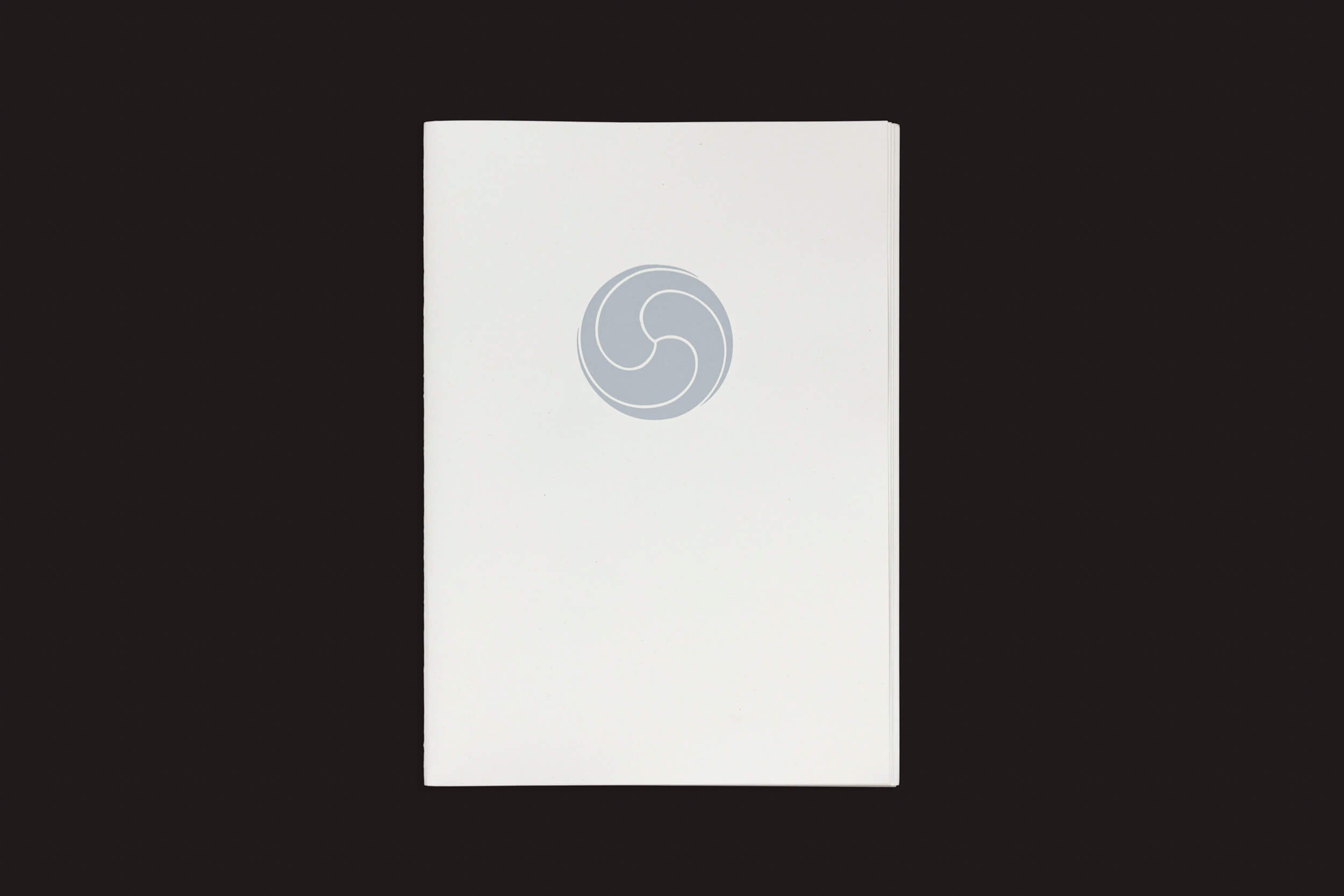A capa apresenta um design circular minimalista e abstrato em tons suaves de cinza contra um fundo branco simples e fundo preto sólido, que lembra um símbolo yin-yang. Ele evoca sutilmente fruto e tierra, capturando o equilíbrio harmonioso da natureza em Tierra, Camino, Fruto de Eduard Sánchez Ribot, de Handshake.