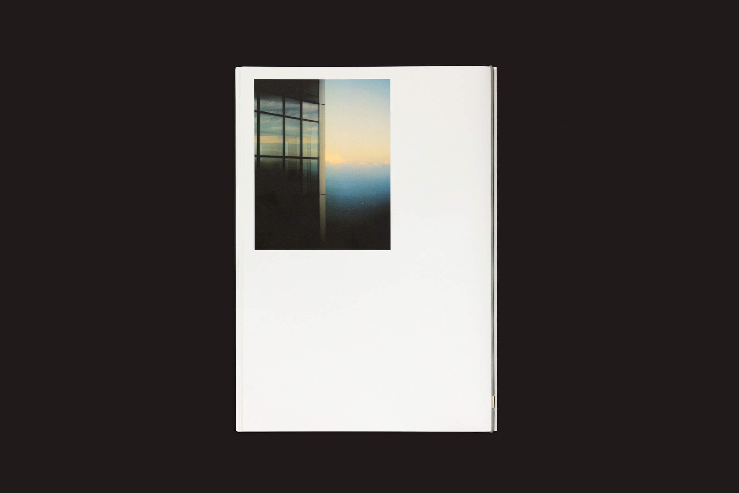 Uma pequena foto de uma porta aberta para uma paisagem enevoada do pôr do sol encabeça uma página em branco, incorporando a essência de Eduard Sánchez Ribot: Tierra, Camino, Fruto de Handshake, contra um fundo preto.