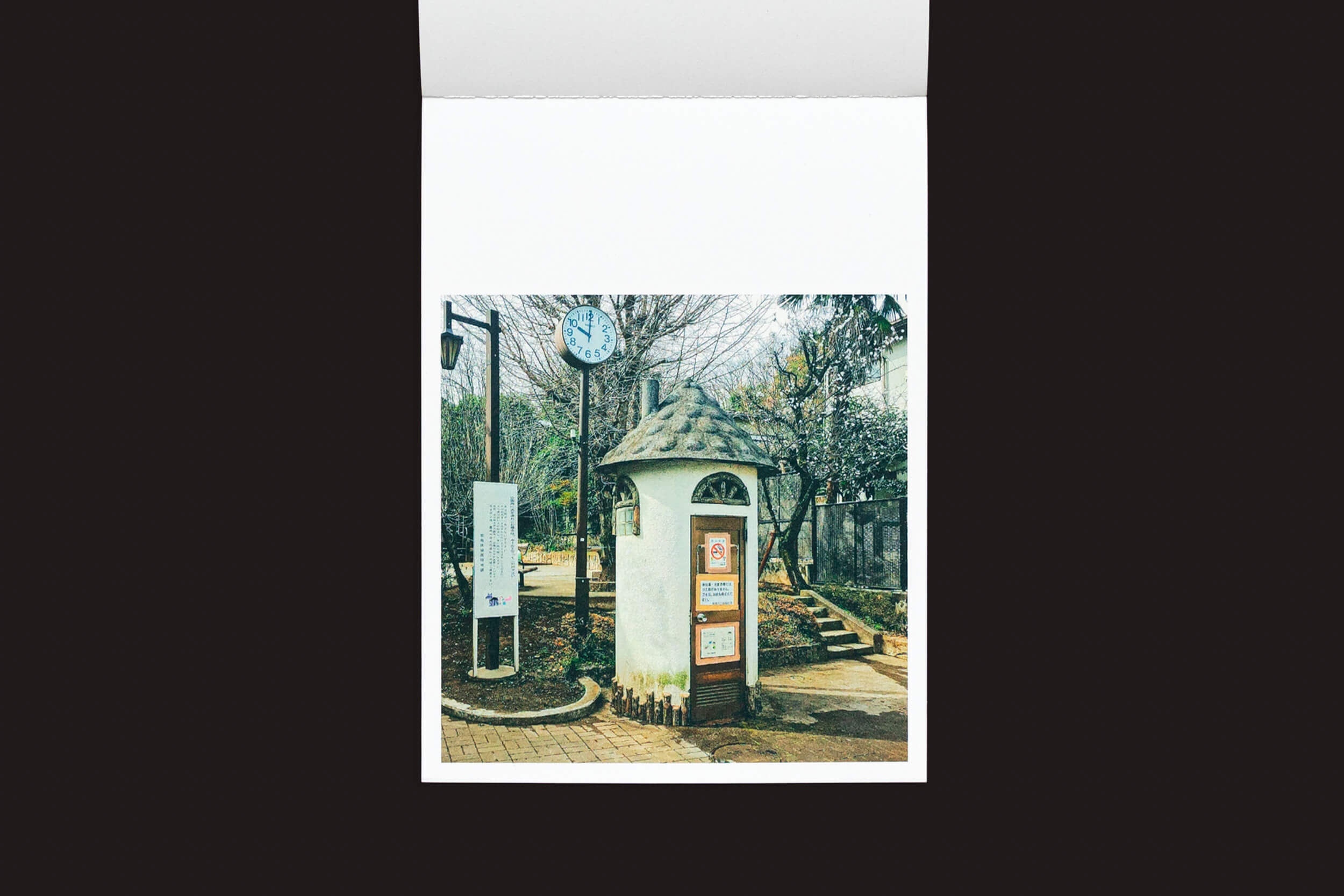 No parque fica um quiosque circular pitoresco com um teto cônico inspirado na arquitetura tradicional japonesa. Perto dali, um relógio montado em um poste mostra as horas. Placas informativas cercam o quiosque, e árvores envolvem a área. É uma reminiscência de Toilets a Go Go! de Hidefumi Nakamura, do Handshake.