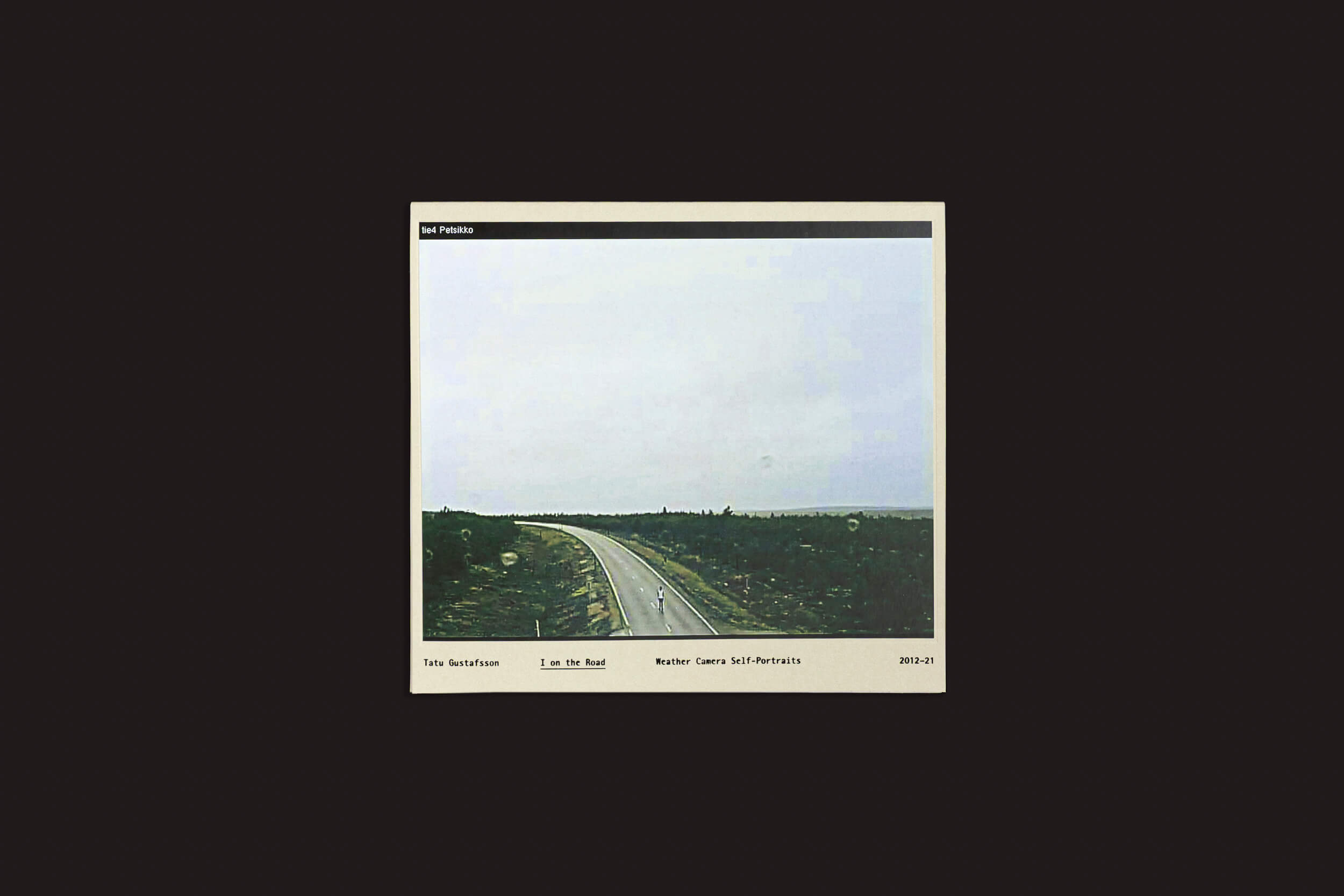 Uma estrada deserta sob um céu nublado captura um estilo de fotografia alternativo em "I on the Road / Weather Camera Self-Portraits, 2012-2021" de Tatu Gustafsson, da Fw:Books, explorando abordagens únicas de autorretrato.