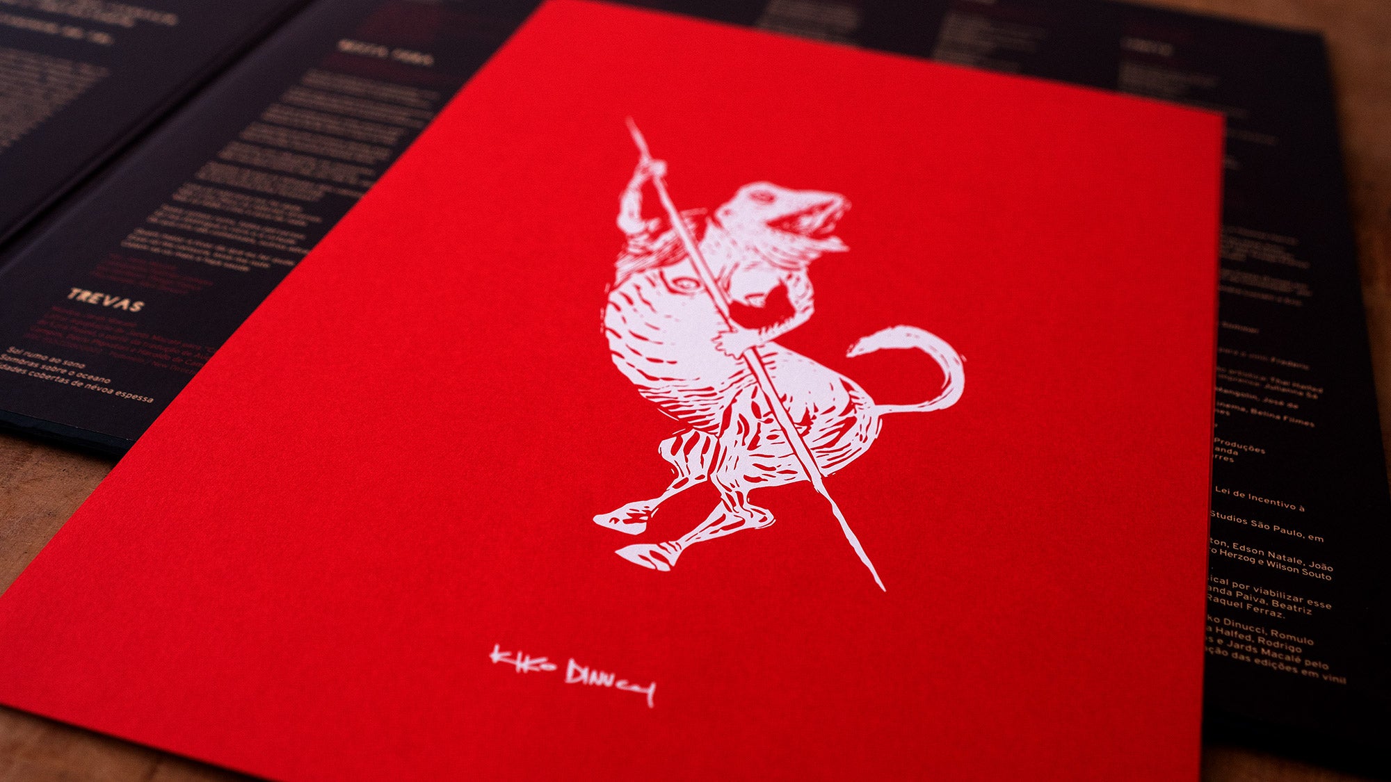Uma capa de cardápio vermelha com uma ilustração branca de um animal em pé segurando uma lança, possivelmente um cachorro ou lobo, apoiado em duas pernas. O fundo mostra cardápios pretos desfocados com texto em branco e dourado.
