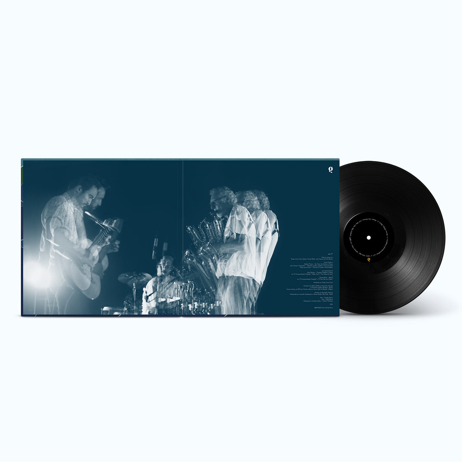 Um disco de vinil parcialmente retirado da capa do álbum, que apresenta uma imagem duplamente exposta e com tonalidade azul de três músicos se apresentando no palco com instrumentos.